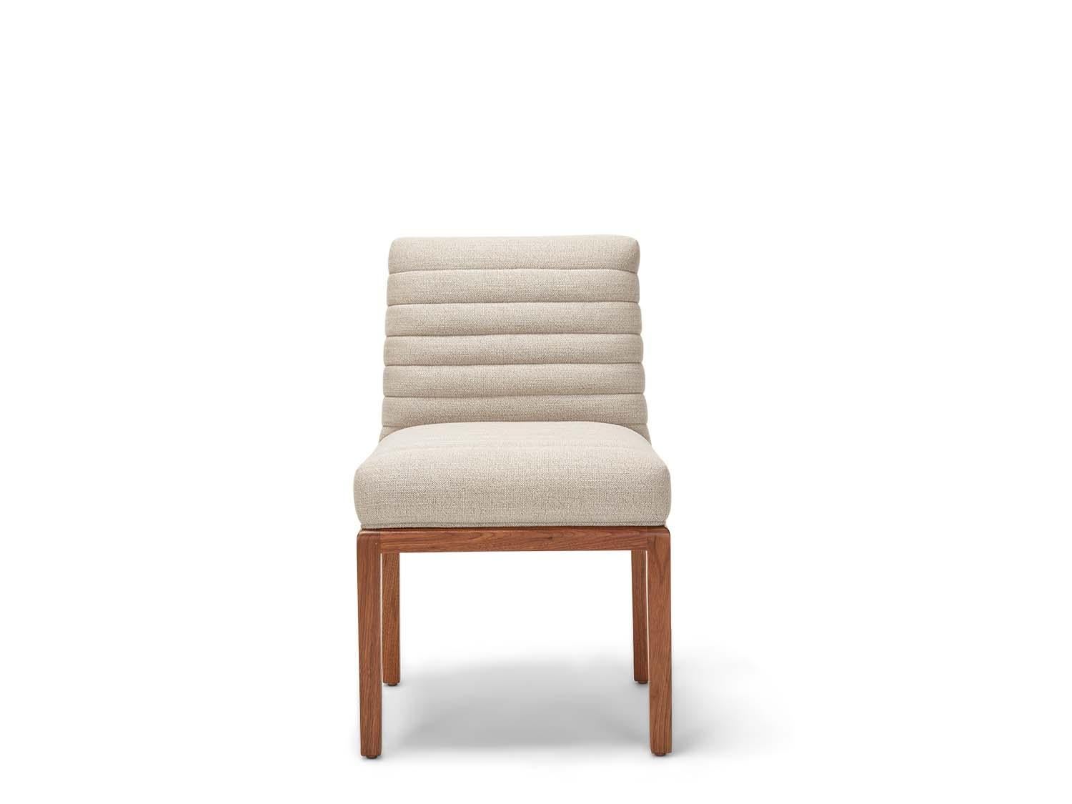 The Shoreland chair is part of the collaborative collection with interior designer Brian Paquette. The dining chair features a channel tufted back and seat with a solid American walnut or white oak frame. This piece is available in exclusive BP for