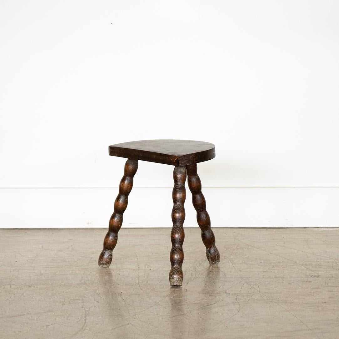 Vintage short wood stool with semi-circle seat and wavy tripod legs from France. Original wood finish with great age markings and patina. Can be used as a stool or as side table next to chairs.
  
 
