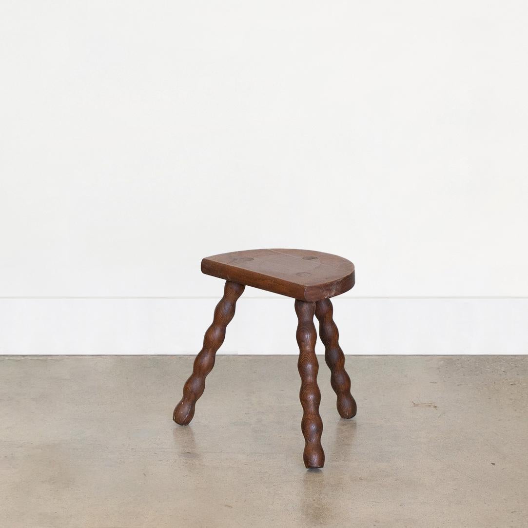 Vintage short wood tripod stool with semi-circle seat and wavy legs from France. Original wood finish with great age markings and patina. Can be used as a stool or as side table next to chairs. Two available, sold individually. 

 