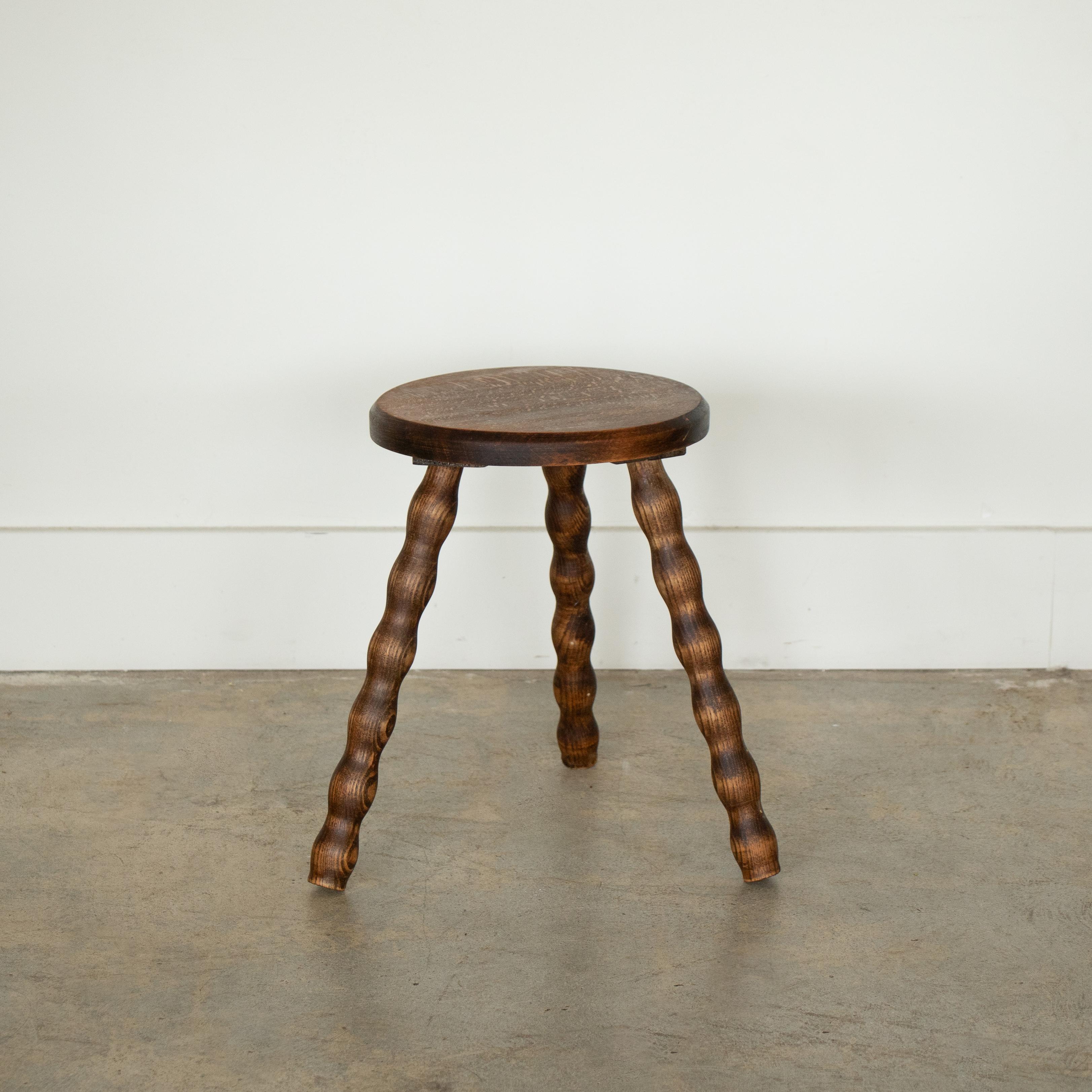Vintage short wood stool with beautiful wavy wood legs and circular seat from France. Original wood finish with great age markings and patina. Can be used as stool or as side table next to chairs. 



