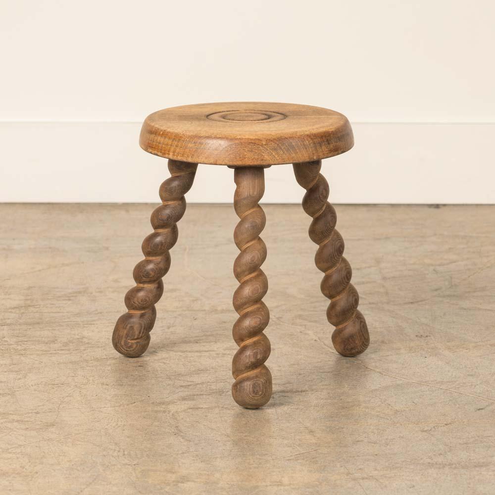 Sgabello corto in legno vintage con bellissime gambe in legno contorto e seduta circolare, proveniente dalla Francia. Finitura originale in legno con grandi segni dell'età e patina. Può essere utilizzato come sgabello o come tavolino accanto alle
