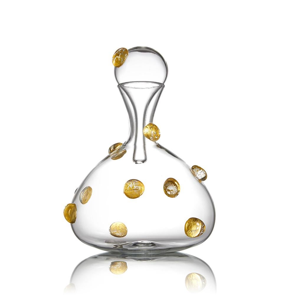The Festa collection of hand blown glass decanters and barware features a celebratory, golden confetti pattern of optic glass dots. Encased gold leaf is magnified by the raised dot pattern and decorates the surface of each carafe. A festive and