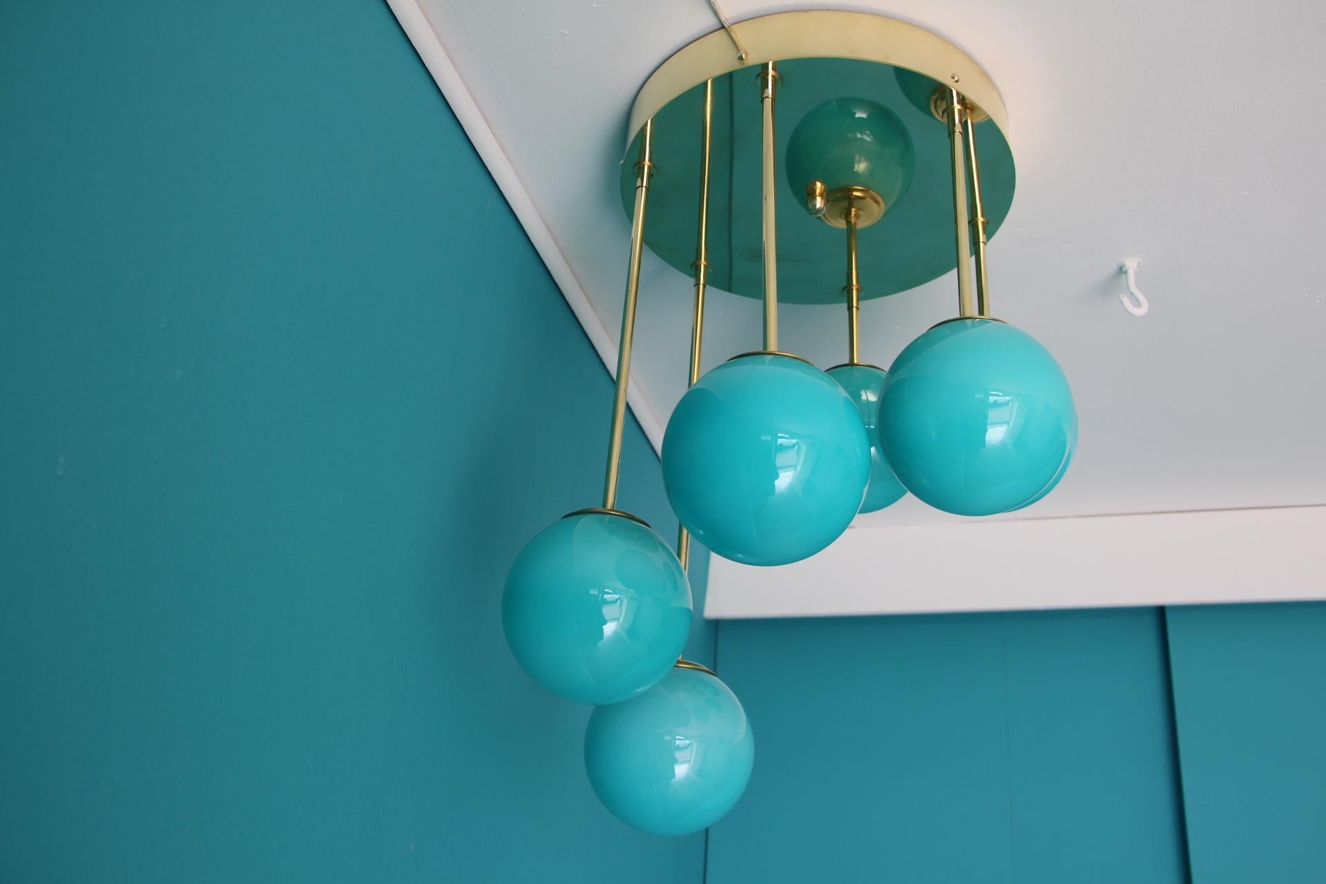 This very nice chandelier features a main brass disk top from which fall 6 brass rods of different length in a spiral shape.
 Each rod is ending with a Murano glass globe.
Each globe was handmade in a magnificent Tiffany blue color.
It gives a