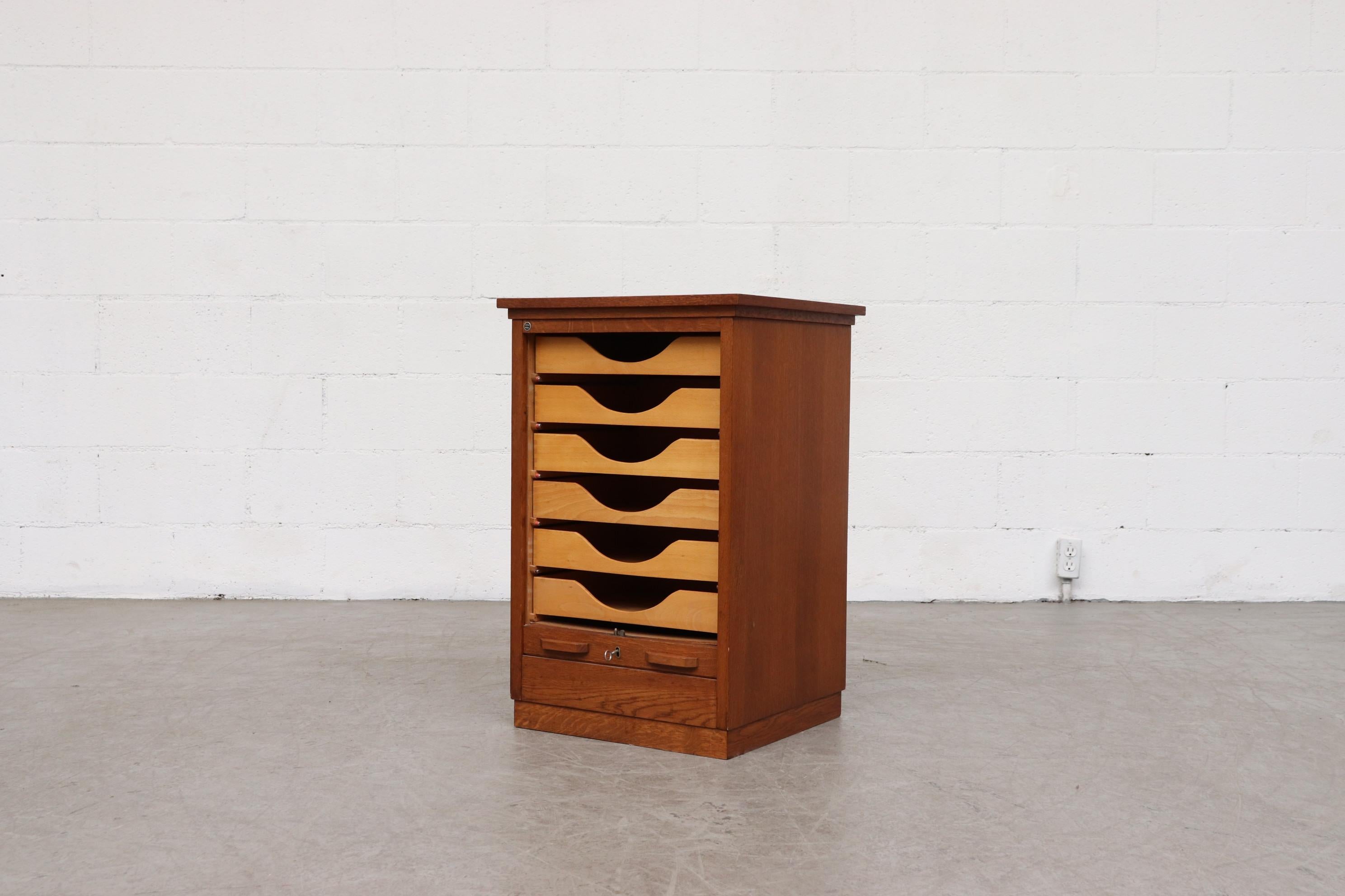 Short oak cabinet by Eeka with tambourd door. Lightly refinished. 6 drawers. In original condition with some visible signs of wear consistent with age and use. Self locking, key included.