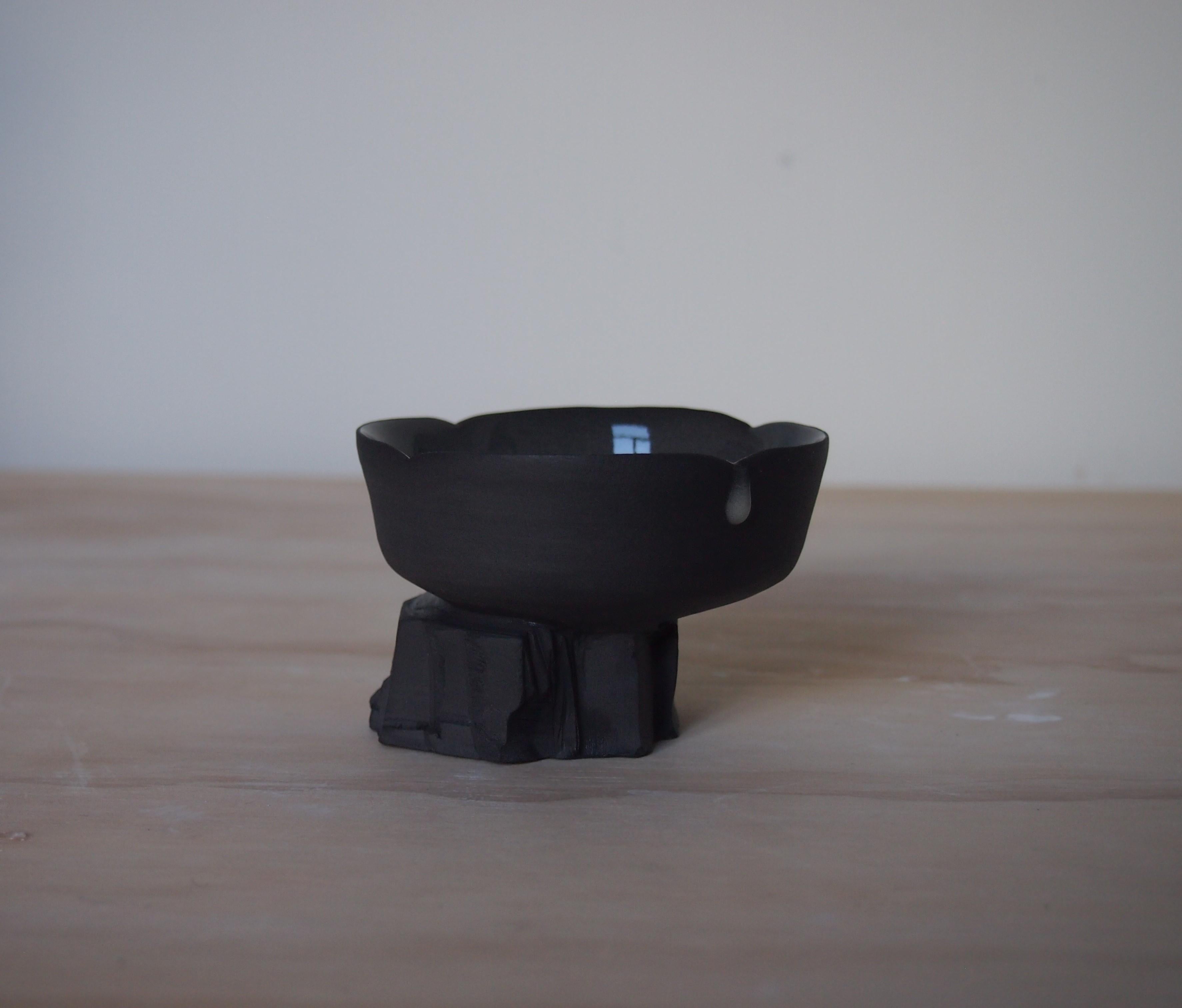 Short Quarry Cup by Liyang Zhang
One Of A Kind.
Dimensions: D 8 x W 8 x H 6 cm.
Materials: Black porcelain. 

Made with single peice of black porcelain. The top is made on the wheel and bottom is made by tearing and chiselling.  The form reveals