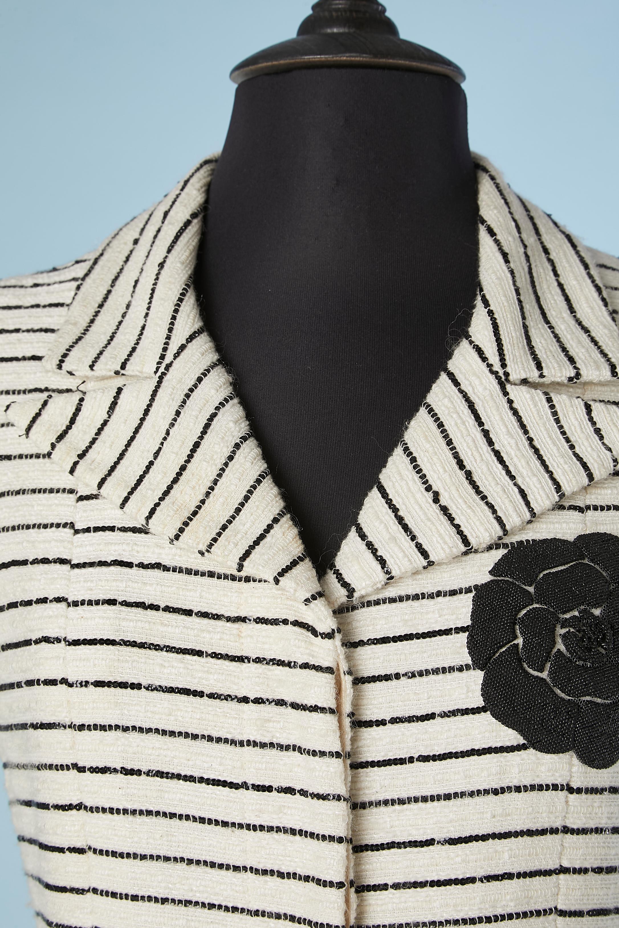 Short sleeves white tweed cocktail dress with black sequin stripes. Black Camelia appliqué in rubber. Mother of pearl buttons. Shoulder pad.
Fabric composition: 48% cotton 24% vinyl 12% nylon 6% wool 5% linen  5% rayon 
Lining: 100% silk ( branded)