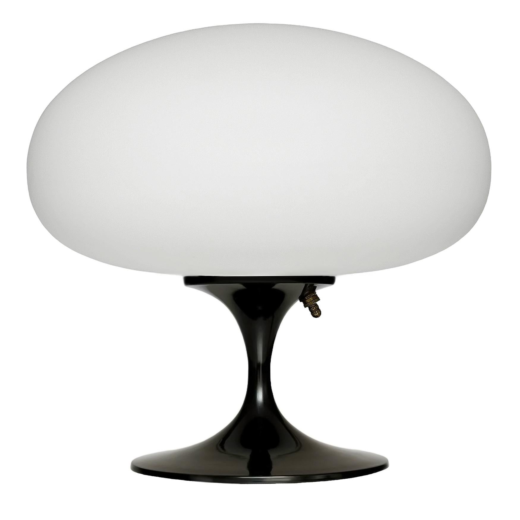 THIS ITEM IS ELIGIBLE FOR FREE SHIPPING!

A sleek stemlite table lamp made by Design Line. It features a cast aluminum main base in a sculptural tulip form. The lamp base is finished in a black gloss color. The frosted glass lamp shade is hand blown