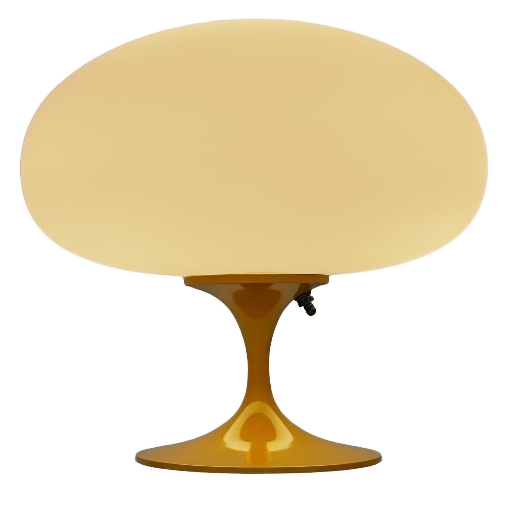 THIS ITEM IS ELIGIBLE FOR FREE SHIPPING!

A sleek stemlite table lamp made by Design Line. It features a cast aluminum main base in a sculptural tulip form. The lamp base is finished in a retro butterscotch yellow color. The frosted glass lamp shade