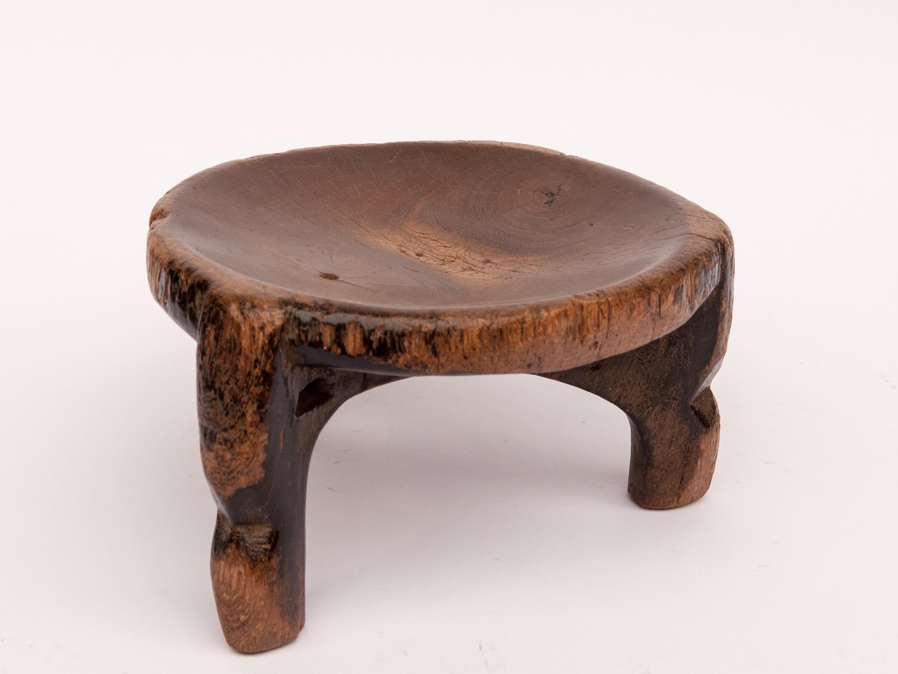 Small tribal wooden stool from Tanzania, mid-20th century. Measures: 10 x 11.5 x 6 inches tall.
This wooden stool possesses a lovely grain pattern. The squat rustic treatment and style of the legs is unusual, and quite charming. It served primarily
