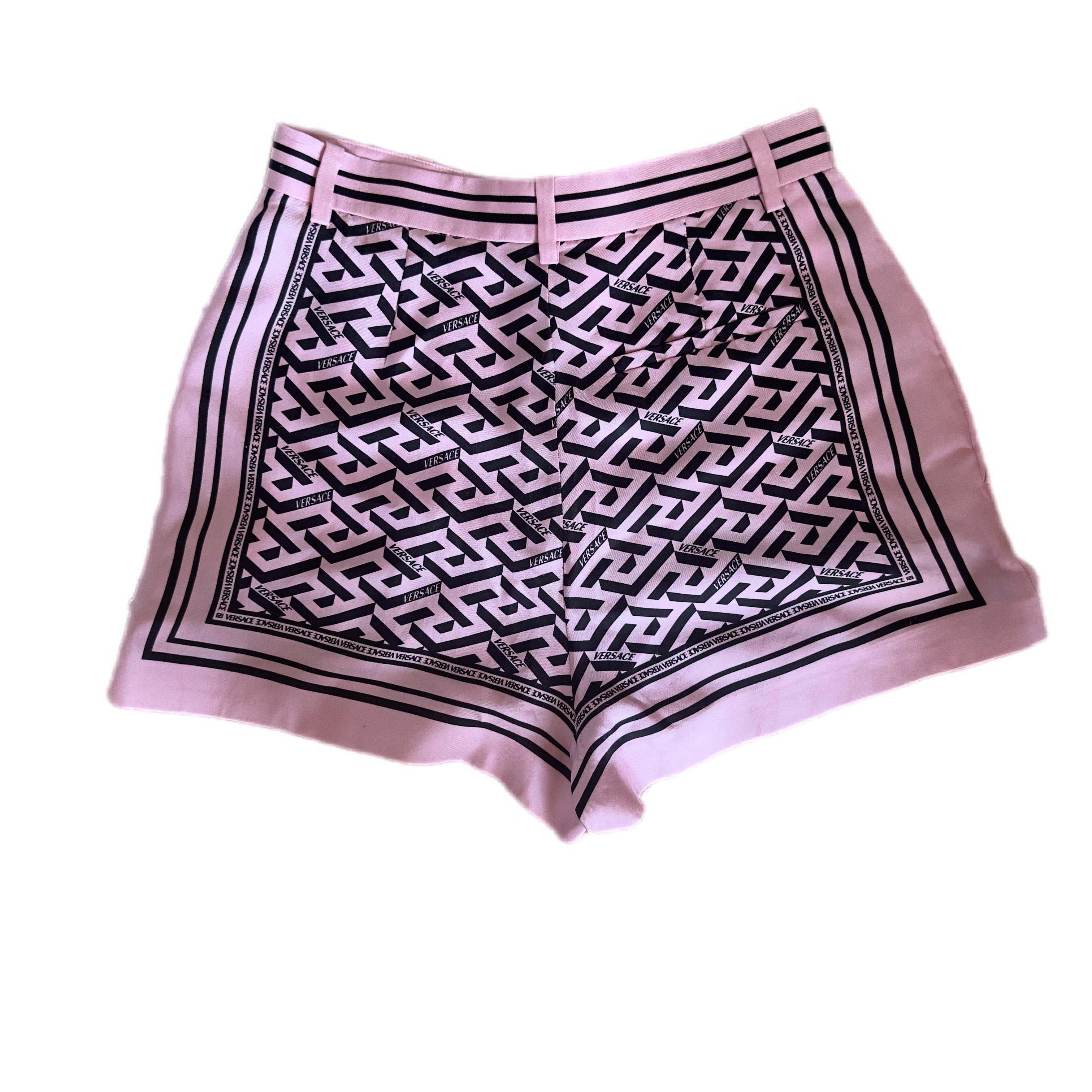 Ikonisch, grafisch und verführerisch: Diese Shorts aus reiner Seide von Versace sind eine Explosion von Weiblichkeit und Charakter. Das Design ist mit dem berühmten griechischen Labyrinth-Print in einer rosa und schwarzen Version verziert, mit einem