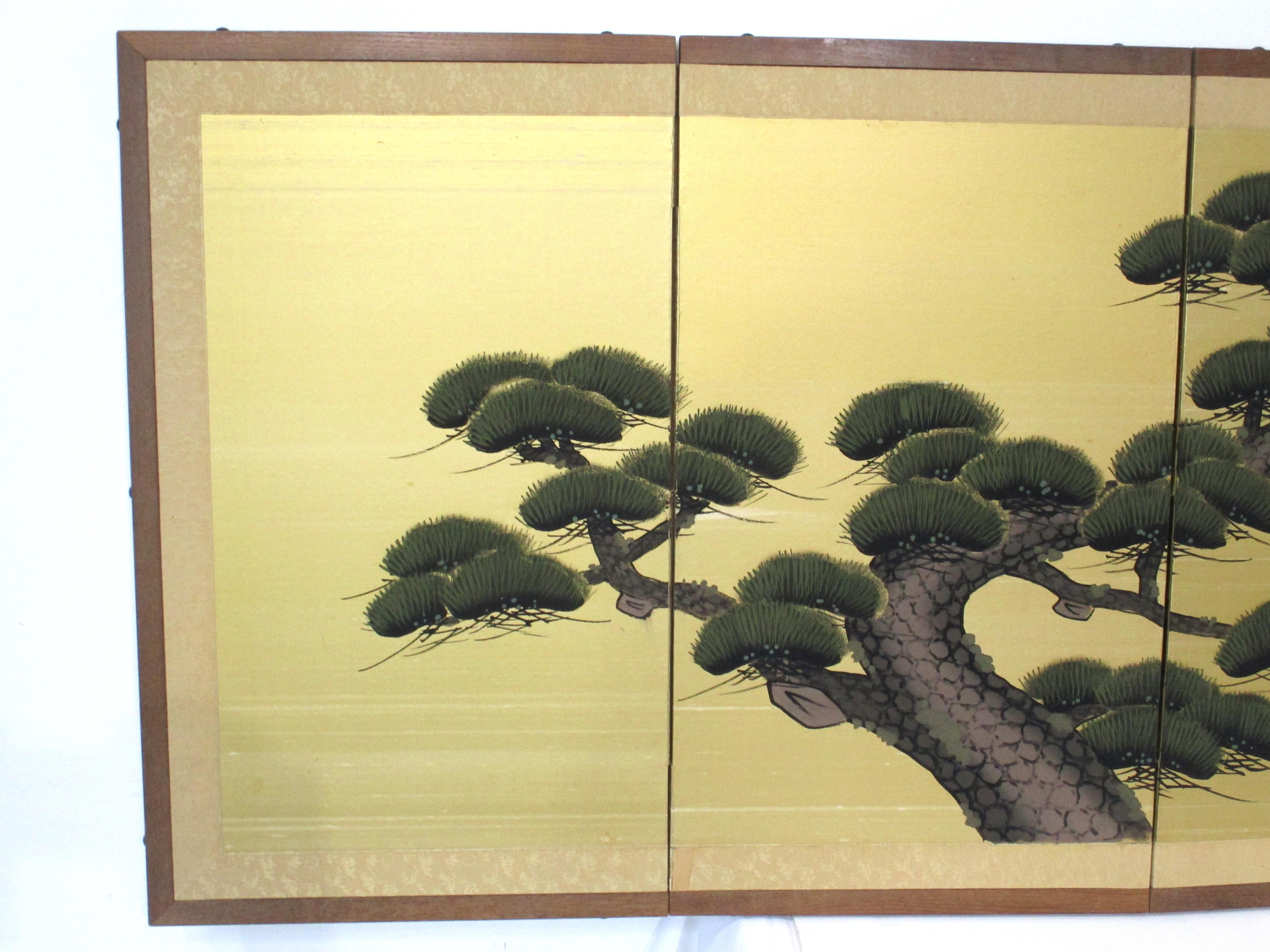 A very well crafted and hand painted smaller four panel Japanese Byobu silk screen with wooden framing . Picturing in detail a calming natural Japanese pine tree on a gold background in the manner of the Edo and Showa period . Signed by the artist