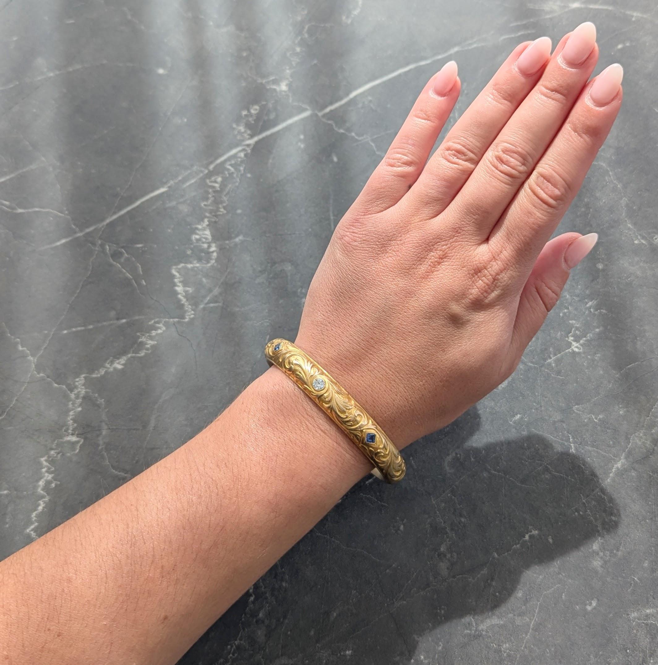 Bracelet de forme ovale avec un motif de volutes en relief.
Centré sur un diamant de taille européenne ancienne pesant environ 0.40 carat au total
Couleur G et pureté VS2 - serti et flanqué de saphirs taillés en escalier sertis.
D'un poids total