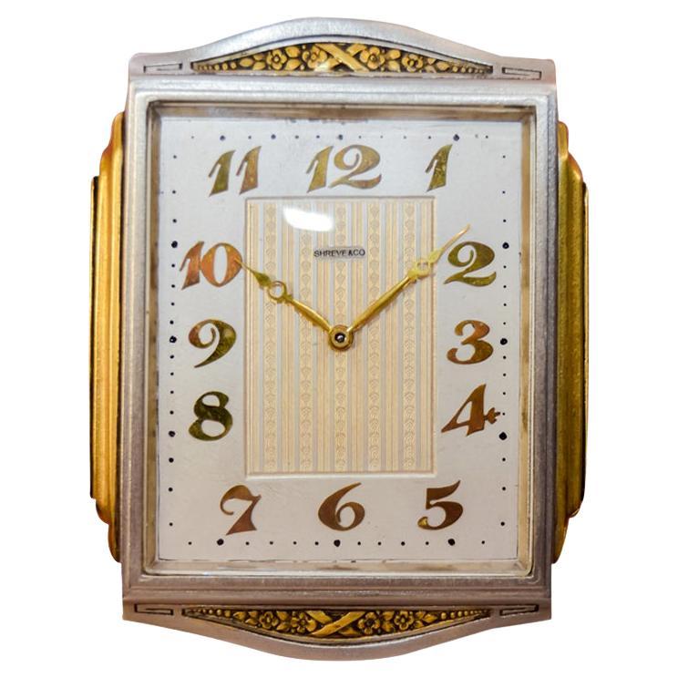FACTORY / HOUSE: Shreve 
STYLE / REFERENCE: Table Clock
METAL / MATERIAL: Nickel Brass Gilded Metal
CIRCA / YEAR: 1930's
DIMENSIONS / SIZE:  Length 5 X Width 4 
MOVEMENT / CALIBER: Manual Winding / 15 Jewels / 8 Days
DIAL / HANDS: Silvered with