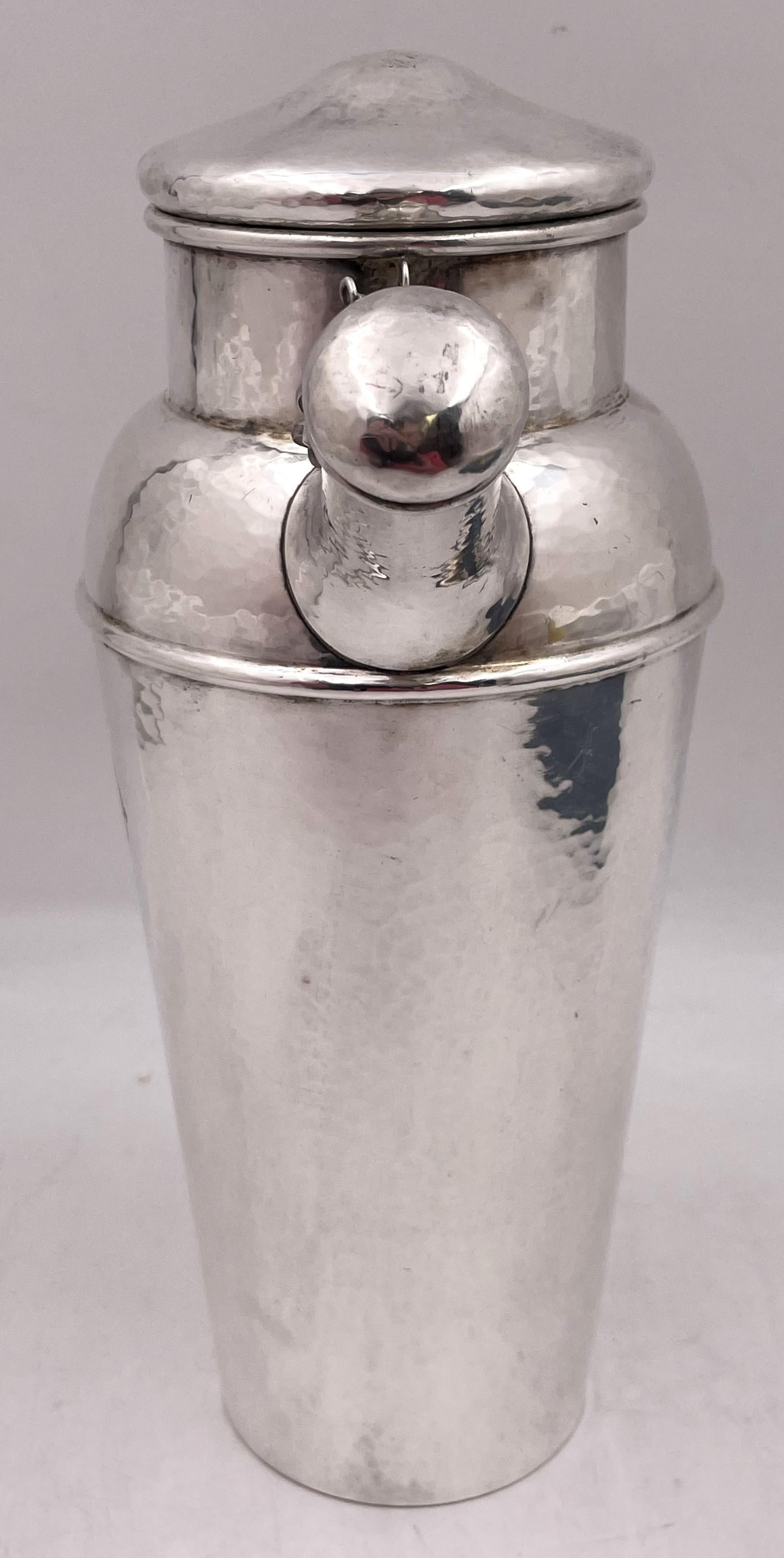 Shreve & Co. sterling silver cocktail shaker from the early 20th century and in Arts & Crafts style, with an elegant, geometric design, all beautifully hand hammered. It measures 10 1/4'' in height by 7 2/3'' from handle to spout by 4 1/2'' in