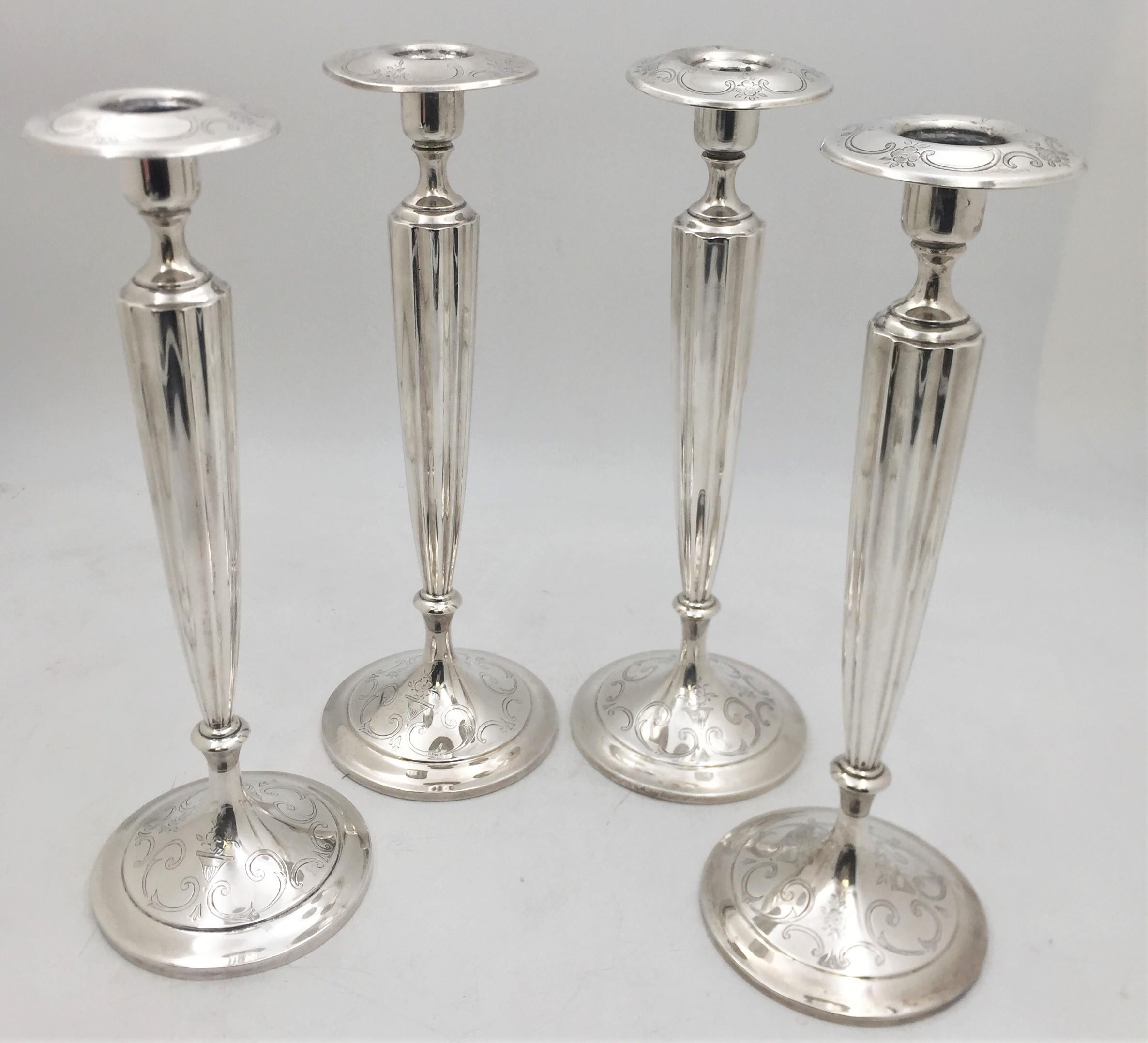 Shreve & Co., sterling silver set of 4 candlesticks from the 20th century, with fluted stems. The rims and bases display floral motifs between elegant swirling designs. Each measures 12 1/3'' in height by 4 1/4'' in diameter at the base, is