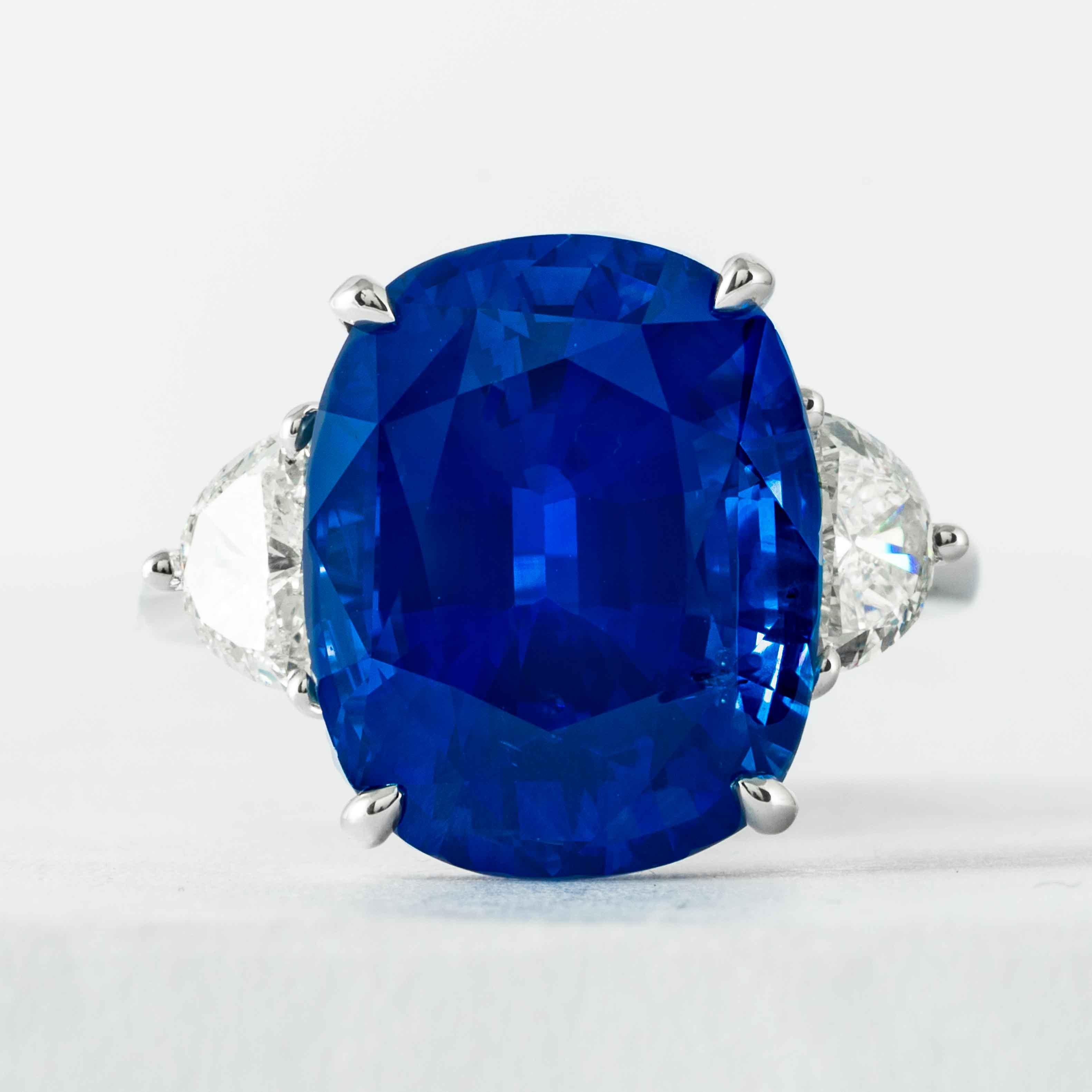 Dieser 3-Stein-Ring mit Saphiren und Diamanten wird von Shreve, Crump & Low angeboten.  Dieser blaue, kissenförmig geschliffene Saphir mit den Maßen 15,06 x 12,18 x 8,25 mm ist in einem handgefertigten, einzigartigen 3-Stein-Ring aus Platin von