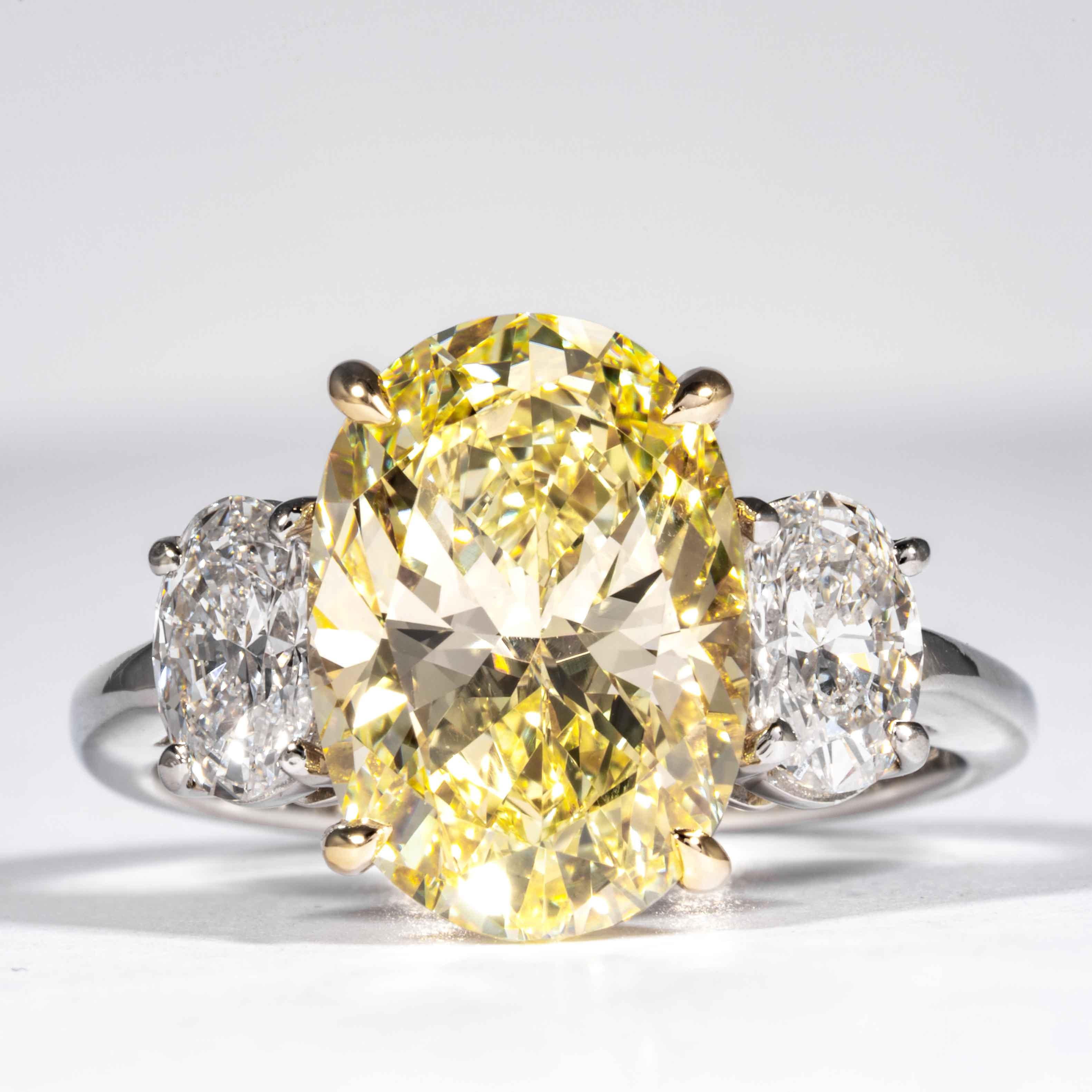 This fancy yellow oval cut diamond is offered by Shreve, Crump & Low.  This fancy yellow oval diamond is custom set in a handcrafted Shreve, Crump & Low platinum and 18 karat yellow gold 3 stone ring consisting of 1 oval cut yellow diamond weighing