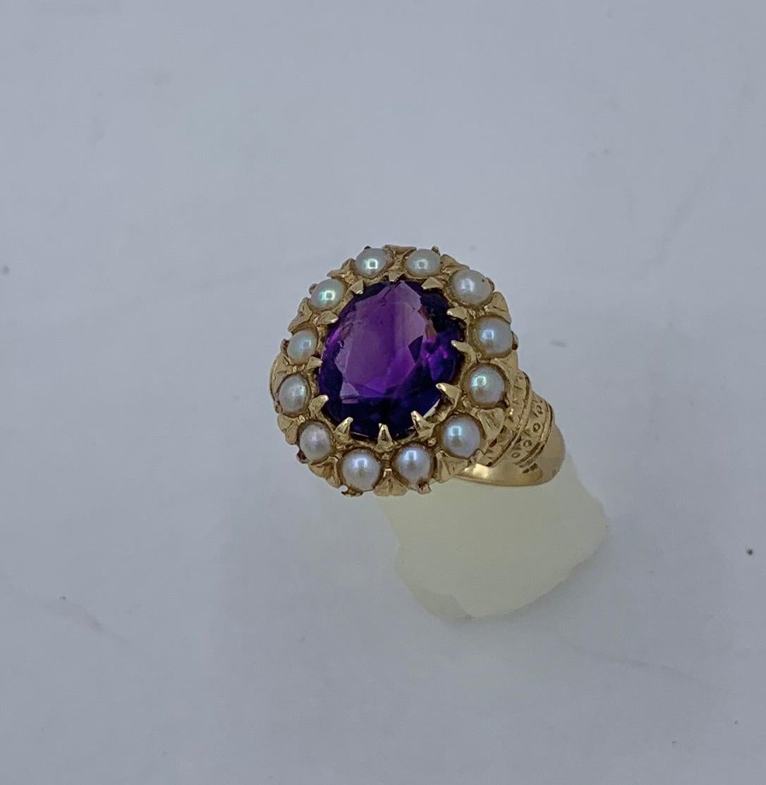 This is a stunning Antique Ring with a beautiful Oval Faceted Siberian Amethyst surrounded by a halo of pearls set in a lovely decorated setting in 14 Karat Yellow Gold.  The oval faceted Amethyst gem is vivid royal purple.  The gem is surrounded by