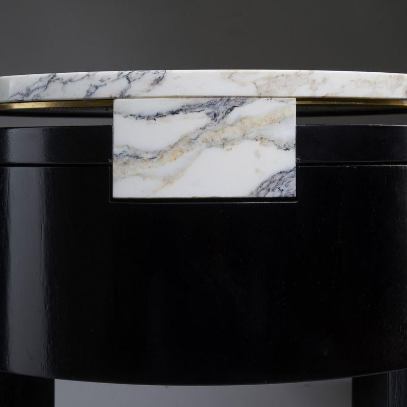 A round bedside table in ebonized varnished walnut with drawer on self-centering sliding guides, central element covered in marble Breccia Medicea, top in marble Breccia Medicea with perimeter wire in brass. Designed by Atelier Avanzi.
 