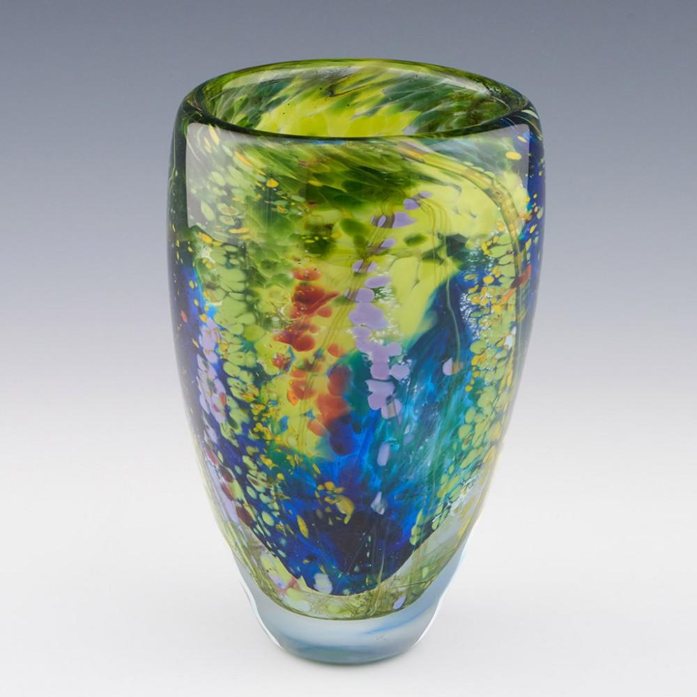 A Siddy Langley 'Spring Garden' pattern open vase made in 2022 in Devon, England. The bowl features a multitude of colours - predominantly greens with blue, violet and red 'floral' inclusions, thickly cased in clear glass. Signed to base 'Siddy