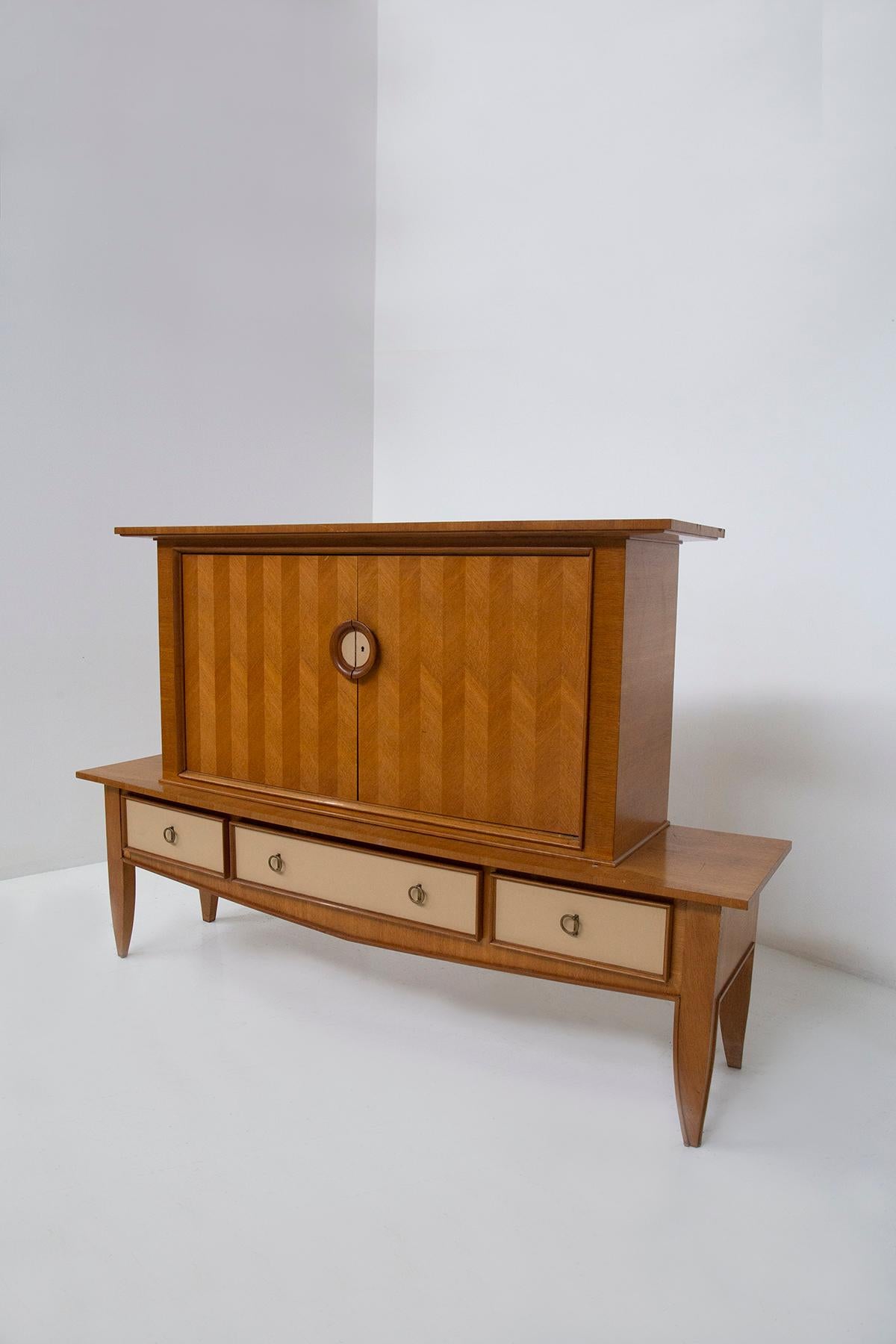 Ce meuble de salon élégant et raffiné, attribué au maître Eleg ROOMS et créé en 1950, est une véritable œuvre d'art qui enchante par sa facture. Réalisée en bois de chêne, elle bénéficie d'un travail extraordinaire qui mêle différentes essences de