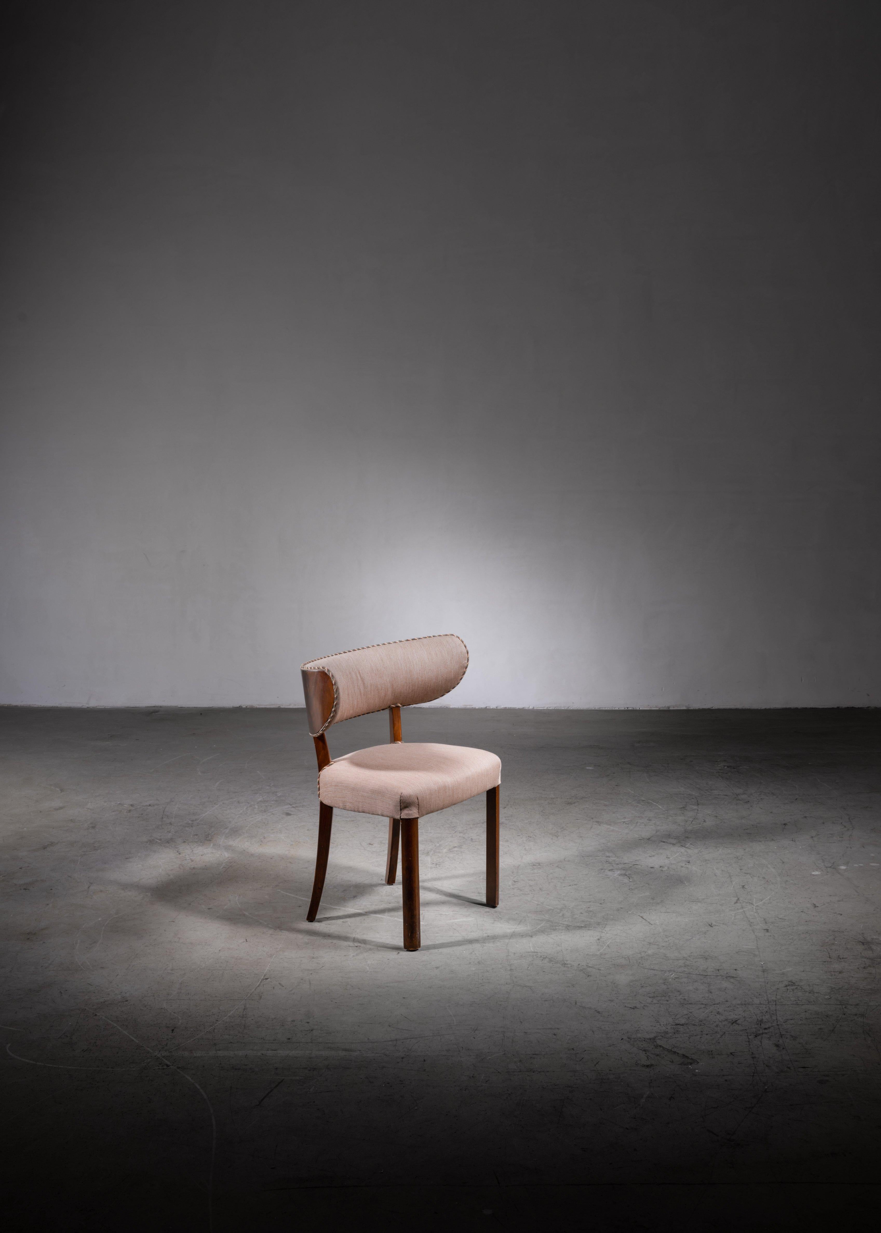 A rare Danish Modern side chair made of mahogany with a grey wool upholstery and a contrasting trim in red, white and green tones. The chair has a beautiful curved and wide backrest and slightly curved back legs, inspired by the classic 'Klismos'