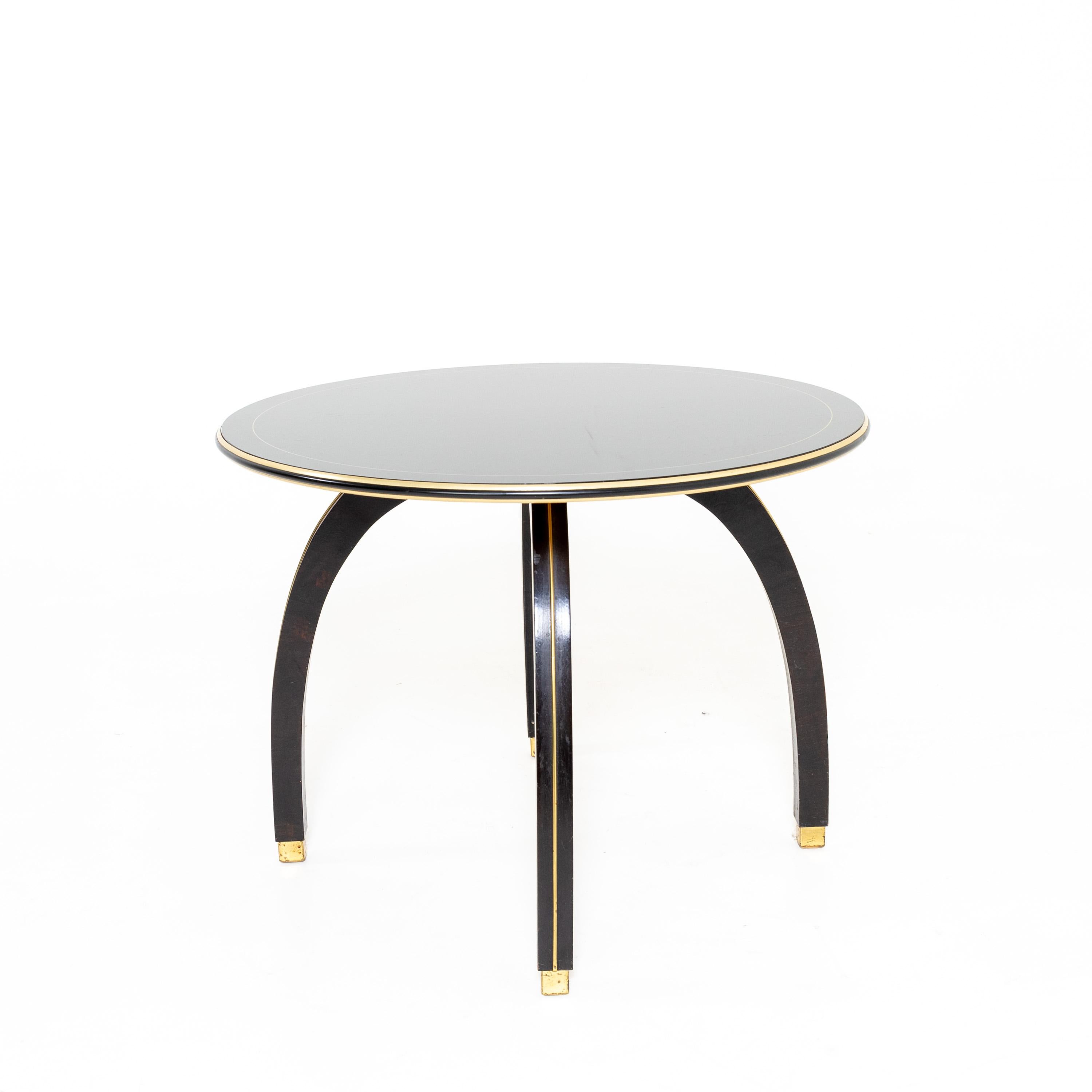 Side table on four curved legs with brass inlay and square brass bases. The round table top also has brass accents.