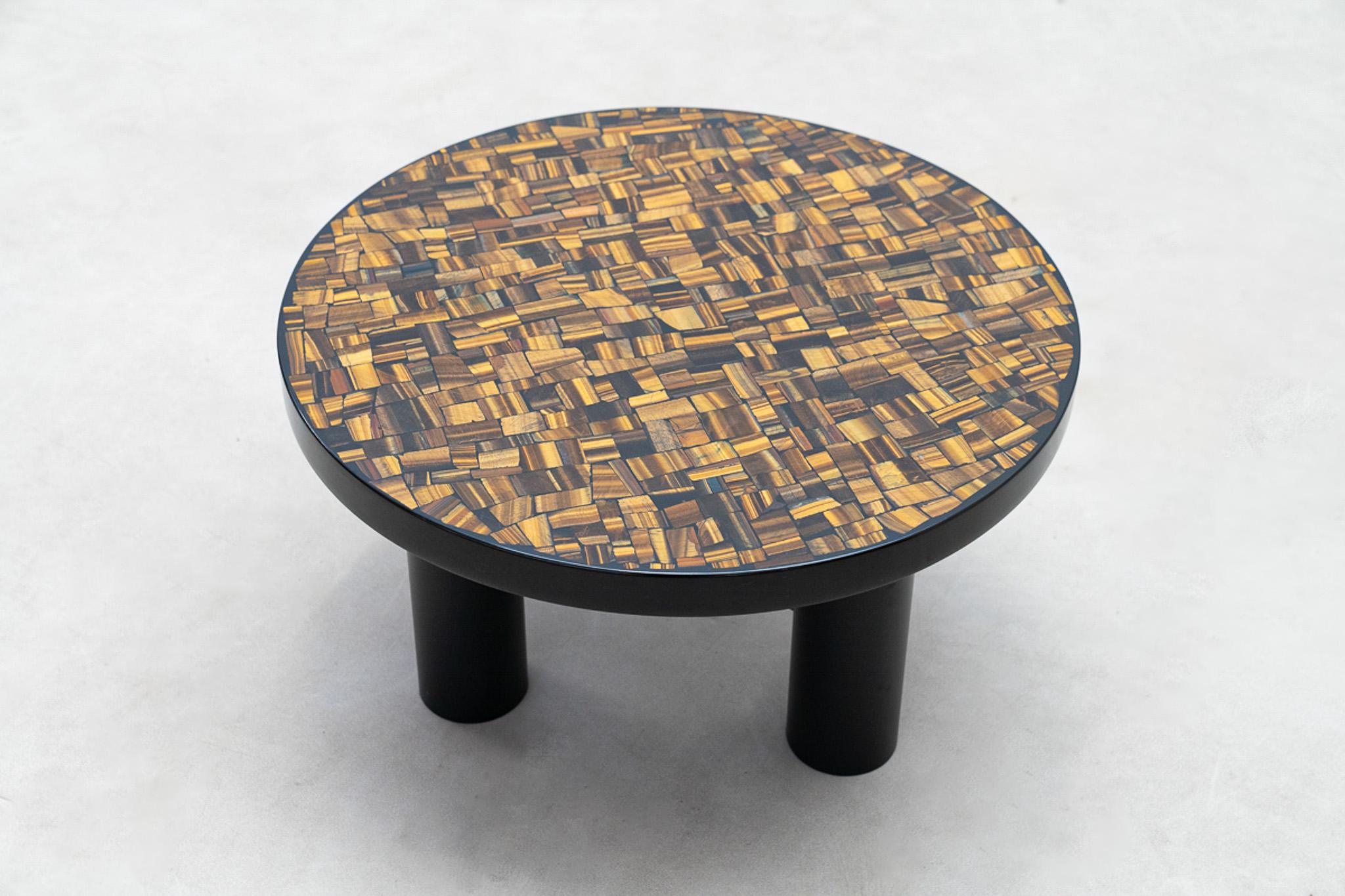 Esta mesa auxiliar del artista belga Etienne Allemeersch tiene un tablero circular con una detallada incrustación de piedras de ojo de tigre engastadas en resina lacada negra. Los patrones naturales y los tonos cálidos del ojo de tigre contrastan