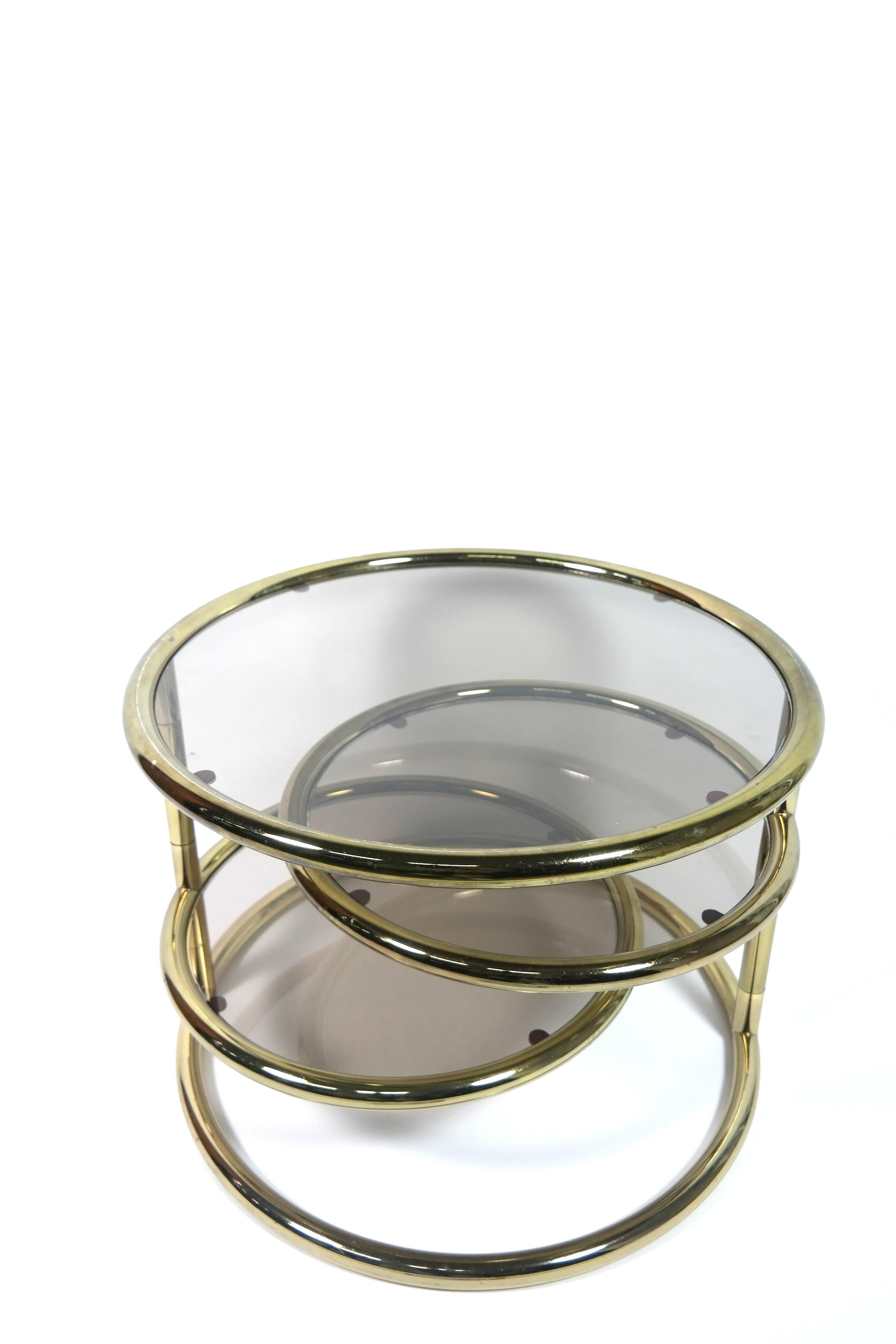 This brass-plated circular side table has two foldable shelves, which can be separately adjusted. It's in great condition.
