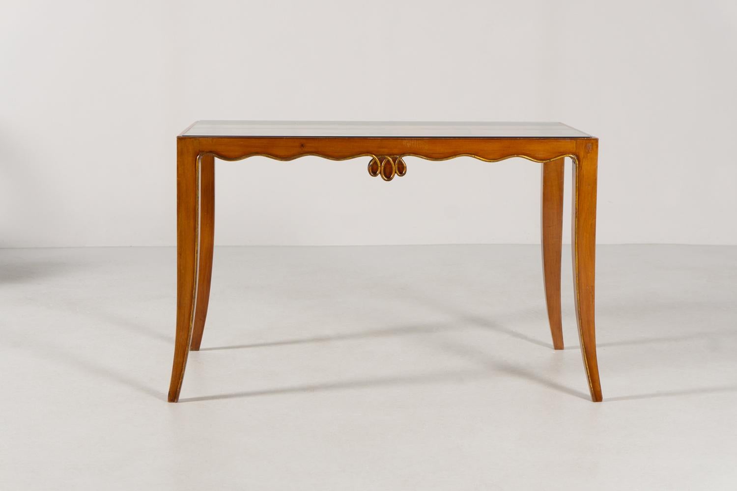 Dieser wunderschöne Tisch von Osvaldo Borsani besticht durch seine schlichte Eleganz. Er wurde 1940 entworfen und besteht aus massivem Nussbaumholz, das teilweise vergoldet ist. Eine Glasplatte vervollständigt diesen eleganten Tisch.