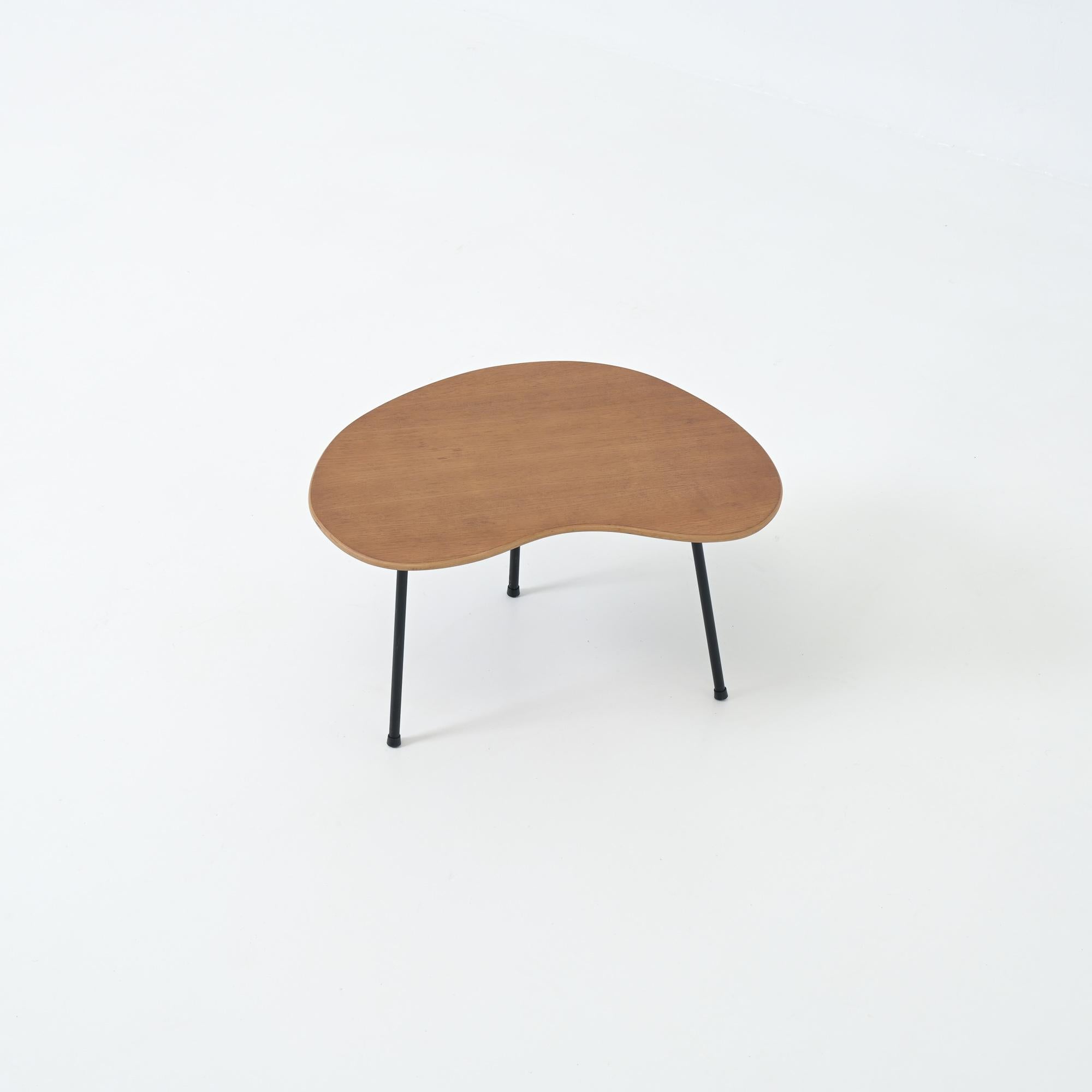 This beautiful kidney shaped side table was designed by Pierre Guariche for Trefac / Meurop Belgium in the fifties.

The wooden top is fixed on a black metal tripod base. It has the same kidney shaped top as the side table of the Prefacto series