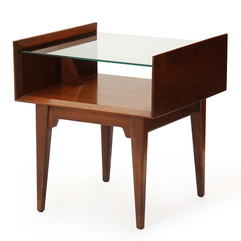 An interesting and finely crafted end table having an architectural form with tapered legs and an expressive apron supporting a floating glass shelf.