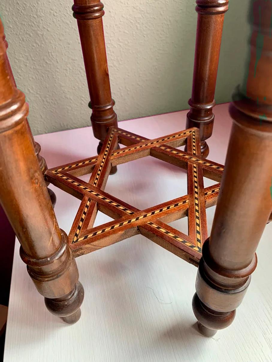Table with very decorative Moorish inlays from the 20th century in a hexagonal shape
This leads to an arched frieze of temple design. The turned legs are supported by a star embedded in the base.  

These table are in good condition, central star