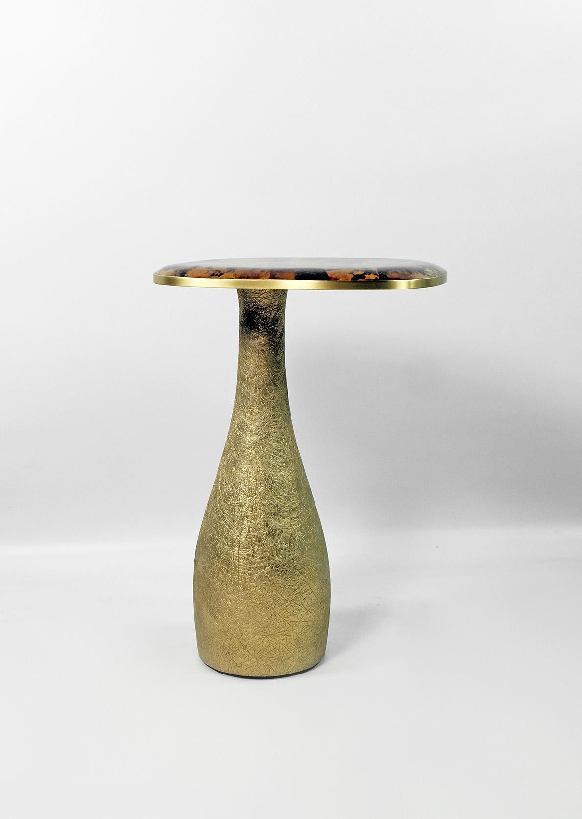 This side table is made of a polished amber yellow marquetry top with brass trims.
This marquetry has a look of turtle shell.
The base is made of wood with a gilded semi-raw glass fiber inlaying.
The semi raw finishing brings an interesting texture