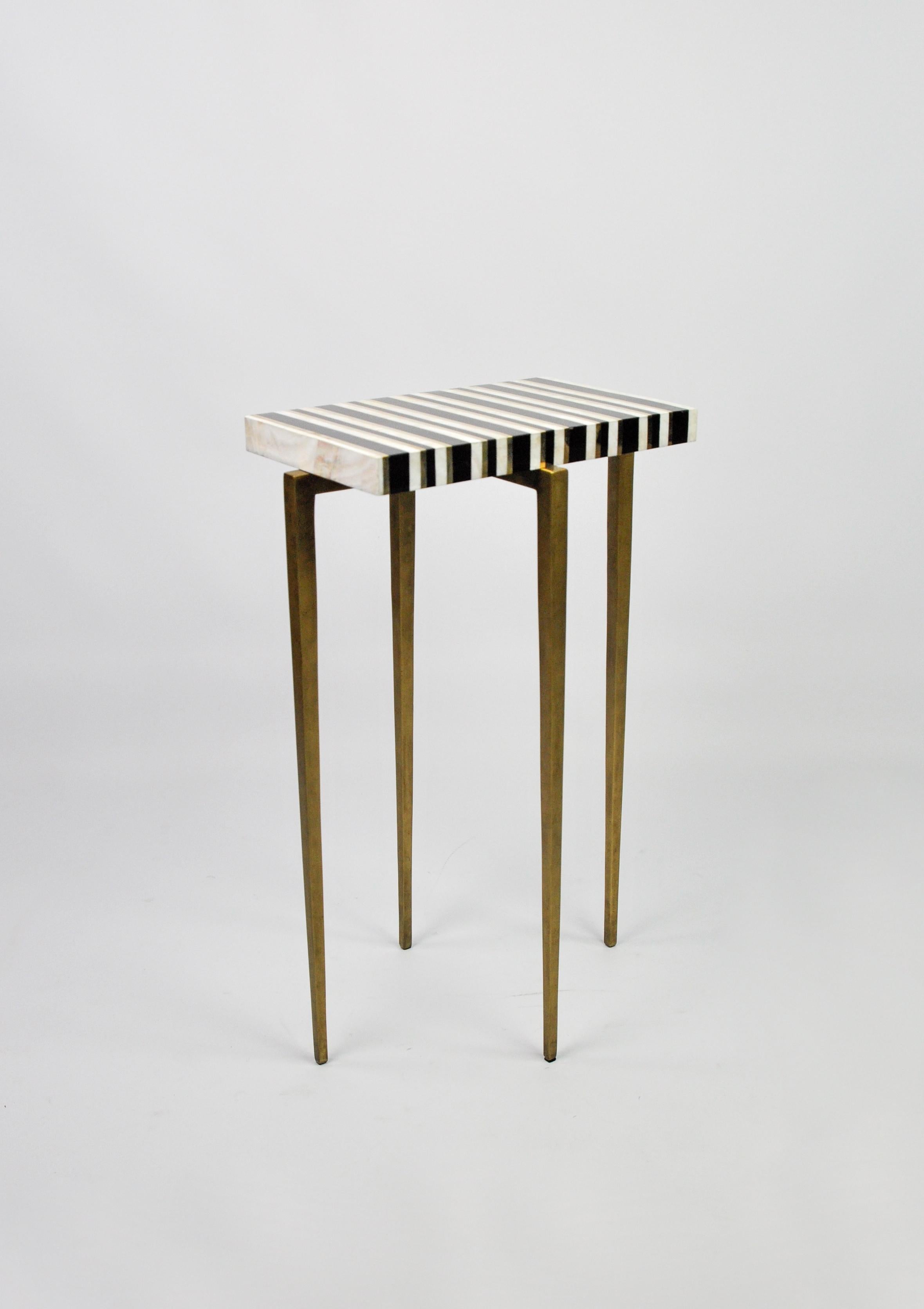 This tiny table is made of polished black and white marquetry with brass trims.

The top is rectangular and the metal feet have an antique brass patina.

The table is small and very versatile. It can be placed anywhere near a sofa and an