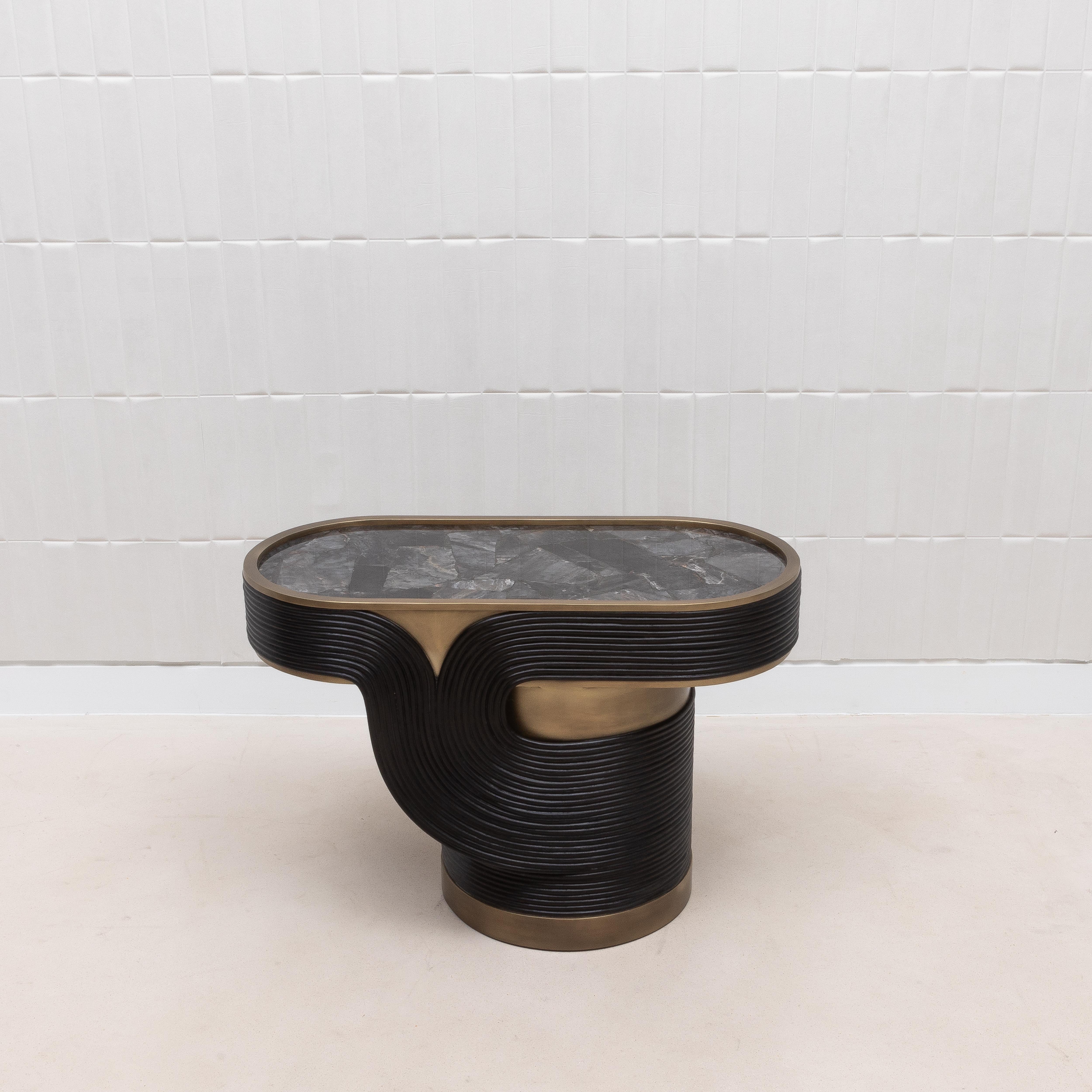 The Licol Side Table is a testament to the artistic finesse of R&Y Augousti, combining the raw beauty of black quartz with the organic elegance of rattan, all encased in a sophisticated bronze patina brass frame. The intricate rattan weaving