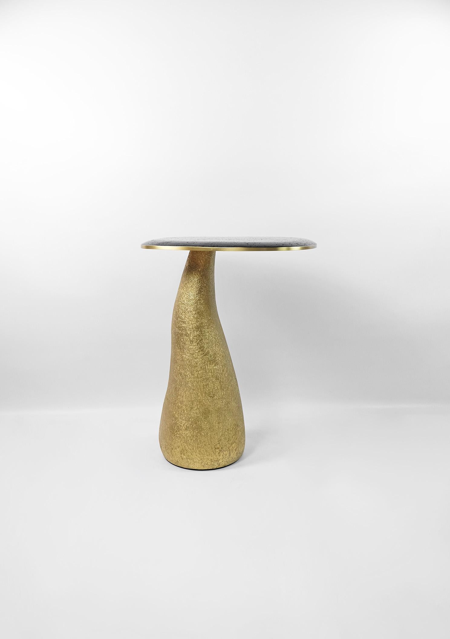 This side table is made of a lava stone marquetry top with brass trims.
The base is made of wood with a gilded semi-raw glass fiber inlaying.
The semi raw finishing brings an interesting texture thanks to the nice organic shape of the tables.

The