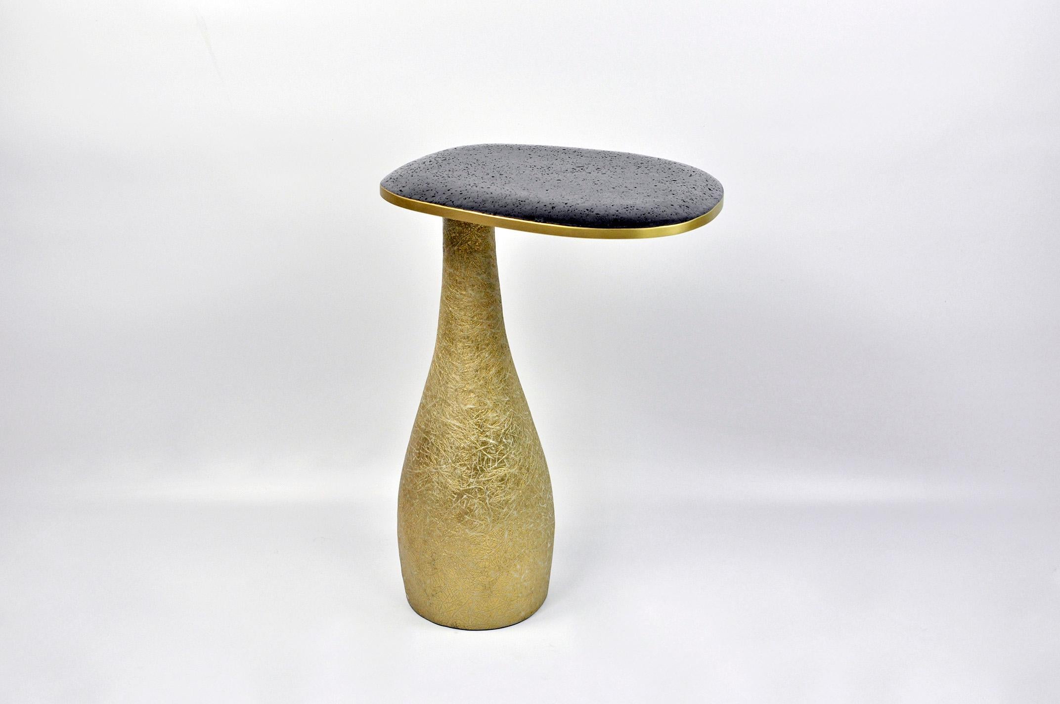 This side table is made of a lava stone marquetry top with brass trims.
The base is made of wood with a gilded semi-raw glass fiber inlaying.
The semi raw finishing brings an interesting texture thanks to the nice organic shape of the tables.

The