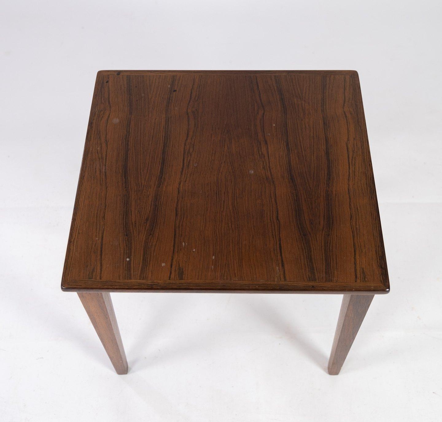 This side table, a product of Danish design from the 1960s, epitomizes the era's dedication to sleek aesthetics and functional elegance. Crafted from luxurious rosewood, it exudes a rich and timeless allure, showcasing the natural beauty of the wood
