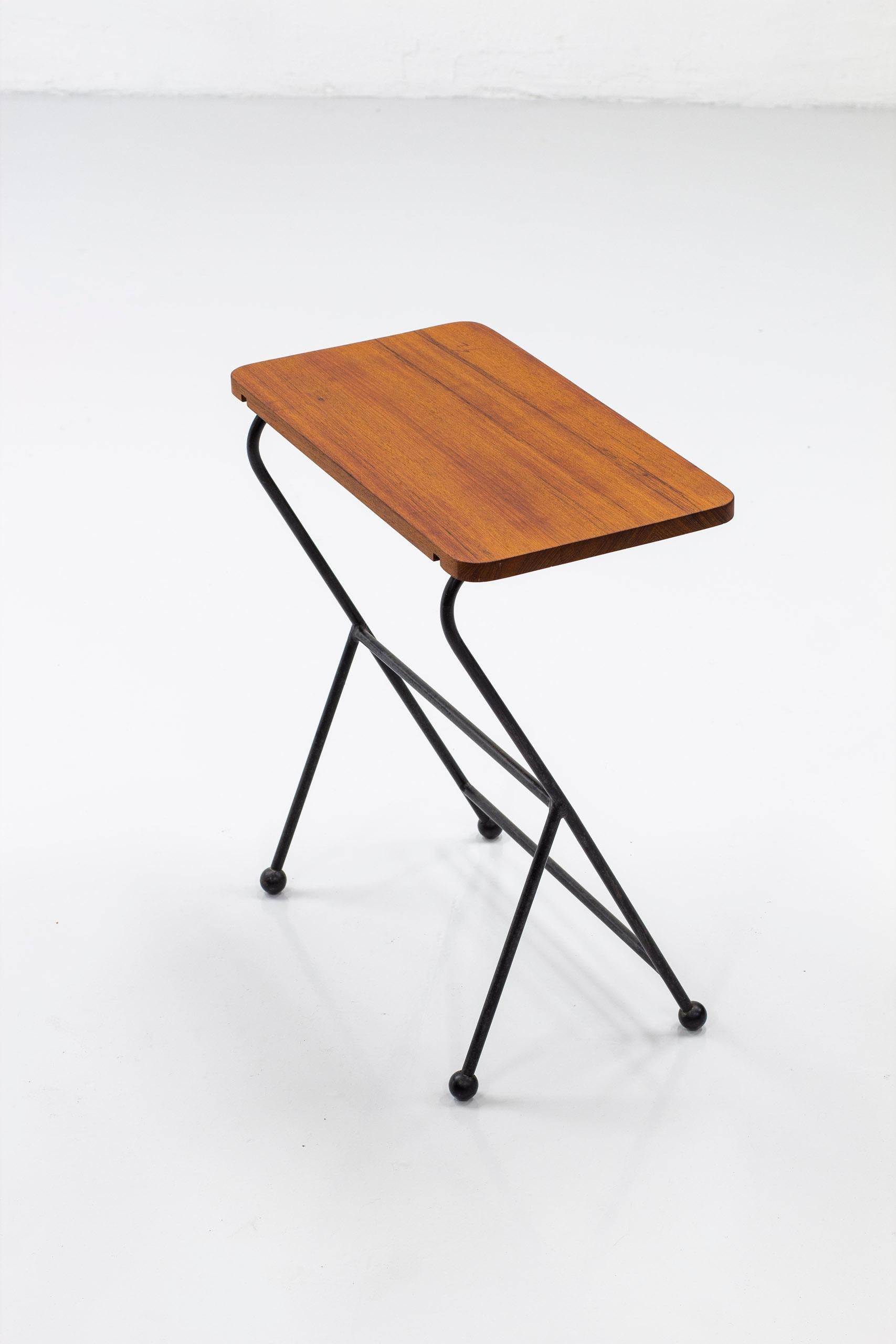 Side table designed and produced in Sweden. Made sometime during the 1950s. Made from black lacquered metal and solid teak table top. Good vintage condition with age related patina from use and wear.