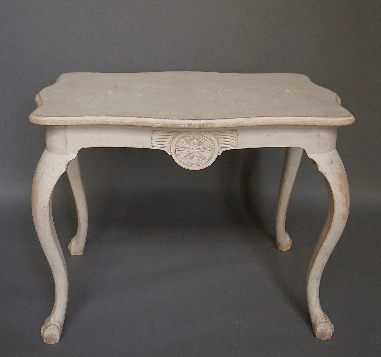 Swedish side table with shaped top, cabriole legs and ball and claw feet. Each side features an unusual carved medallion at the center of the apron. Nice patina.