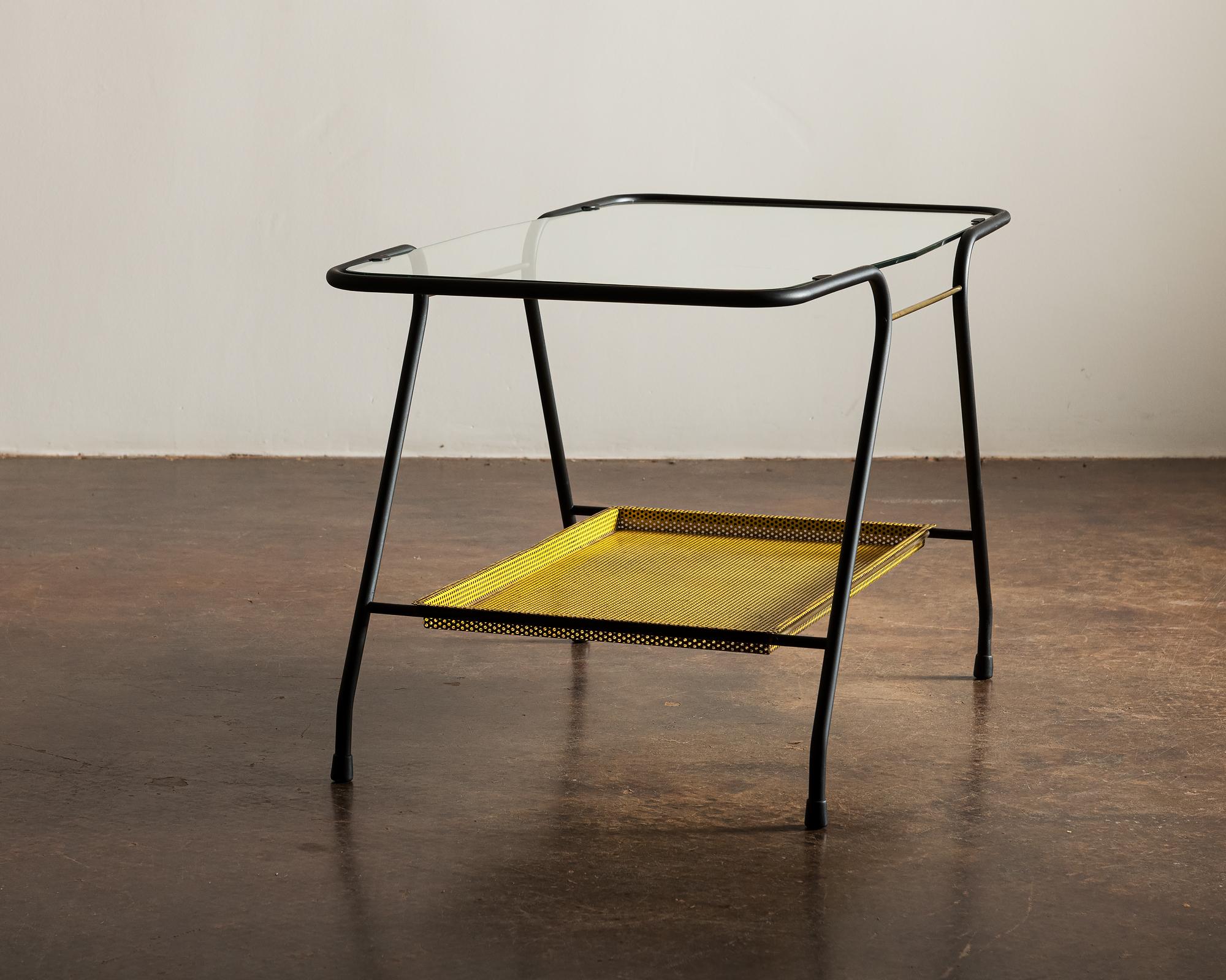 French side table in lacquered tubular metal with perforated bottom shelf, brass accents and top in glass.