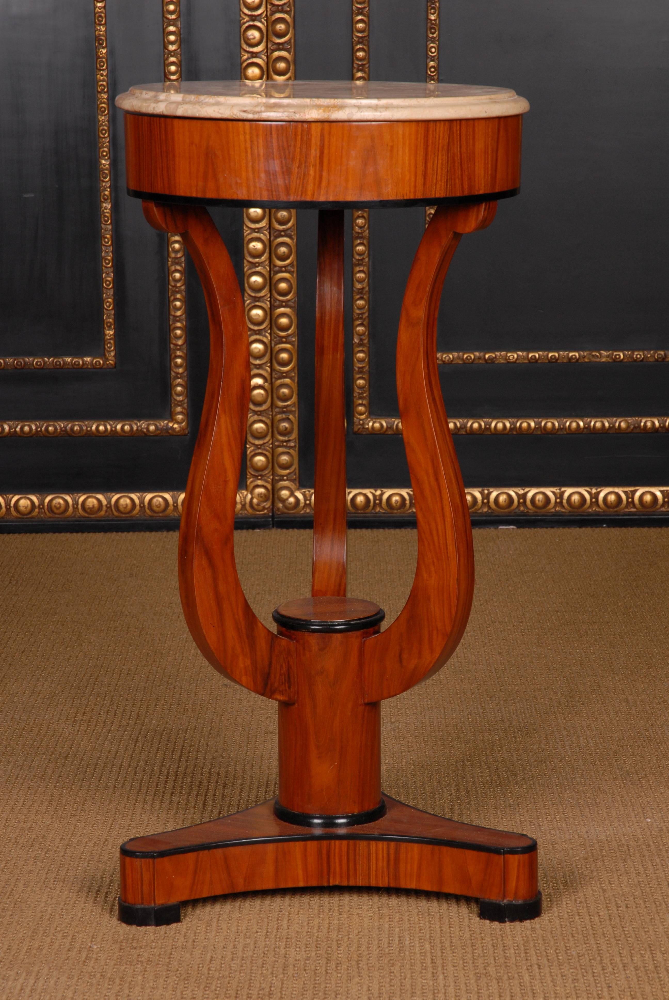 Mahogany on solid wood and partly boned. Round sheet with black-and-white solid marble slab, oversized frame and lyre-shaped curly legs on three-sided base plate and disc feet. This form corresponds to the Viennese Biedermeier and is extremely rare.