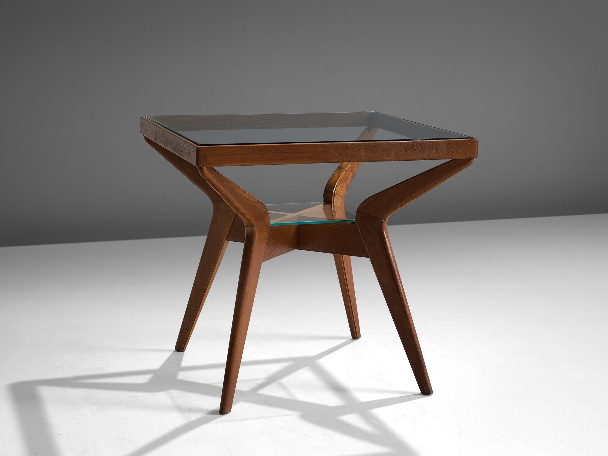 Side table in oak and glass, Italy, 1970s

This small coffee table has a well sized top in glass, framed in a solid wooden square. The top is held by four boomerang shaped legs, with rounded edges and tapered ends. In the middle of the base a small