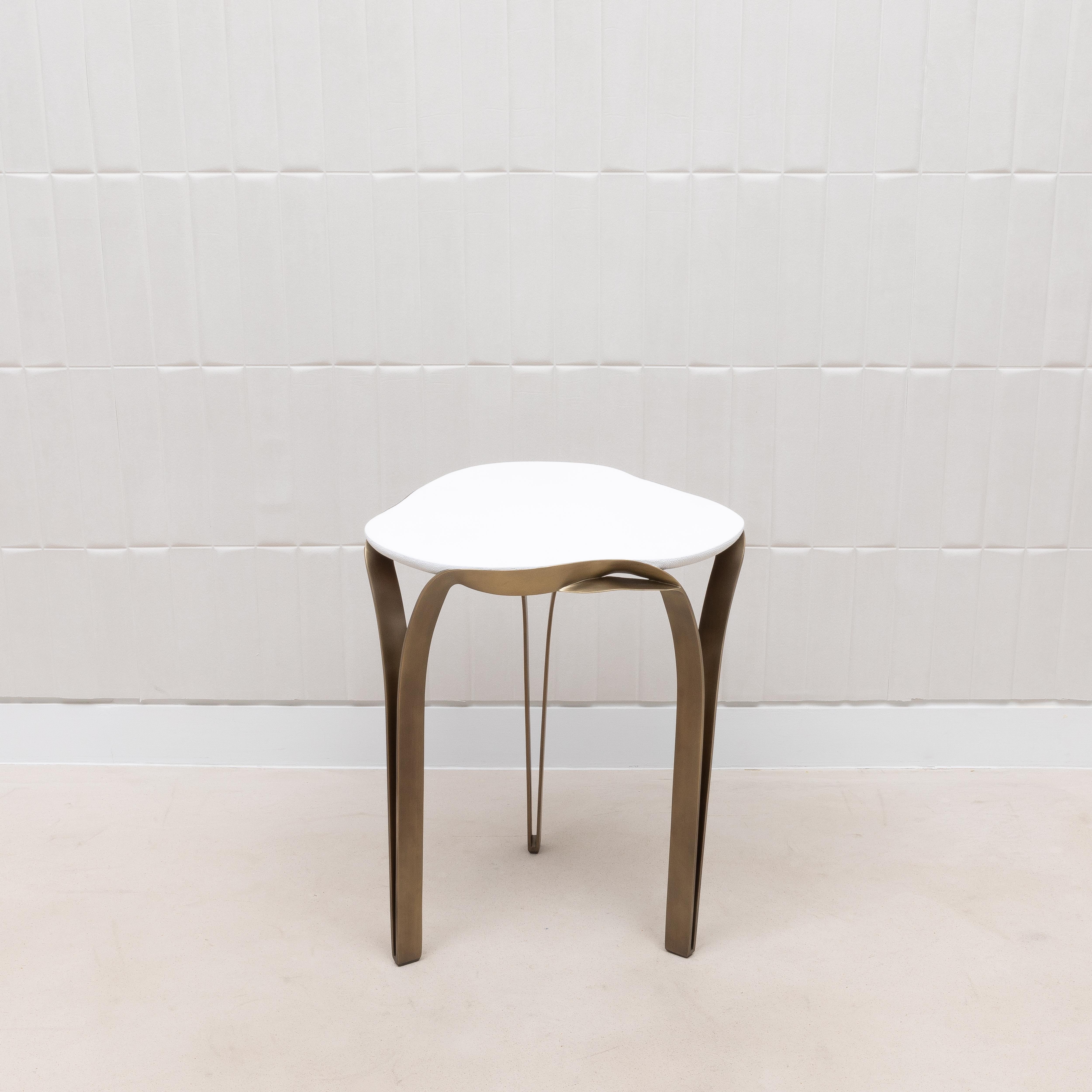 La table d'appoint Angel Falls de R&Y Augousti est la quintessence d'un design opulent, où les matériaux les plus fins rencontrent un savoir-faire exceptionnel. Le plateau de la table, méticuleusement façonné en galuchat blanc lumineux, dégage une
