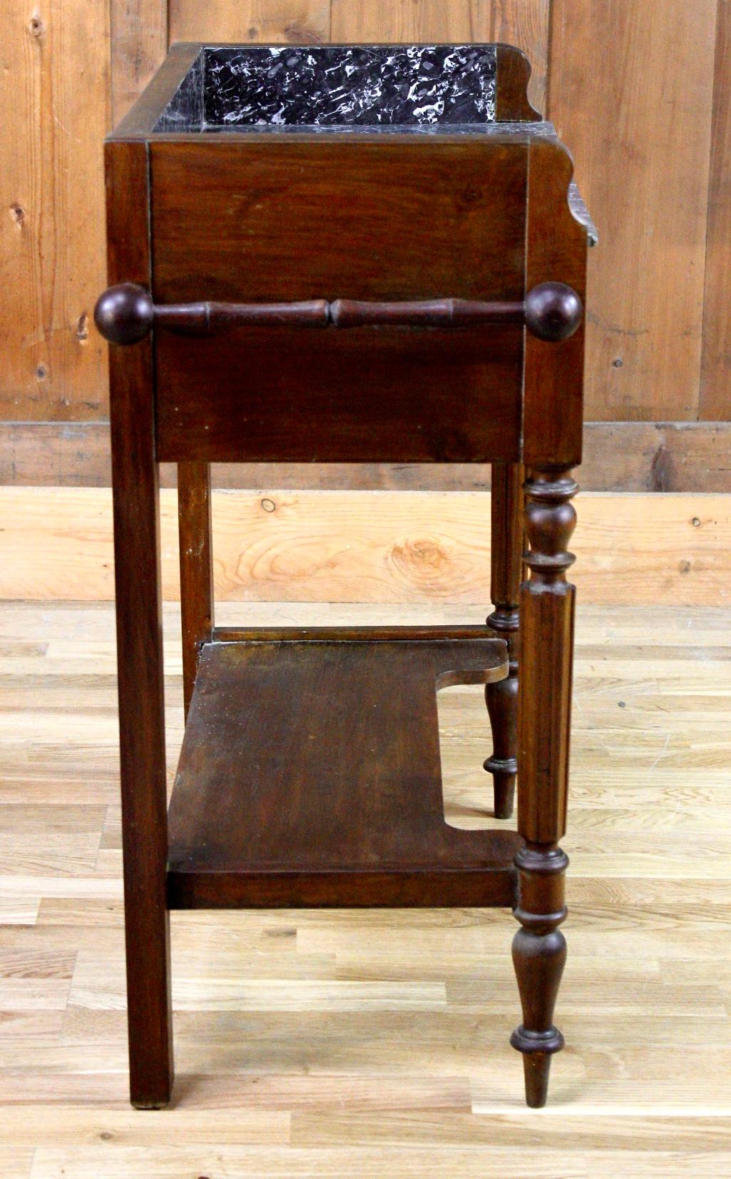 Belle commode en bois et marbre noir datant du milieu du 19e siècle. Cette table est composée de quatre pieds reliés par une étagère. La ceinture est habillée d'un tiroir. Le dessus est en marbre noir et blanc. Des deux côtés du meuble sont présents