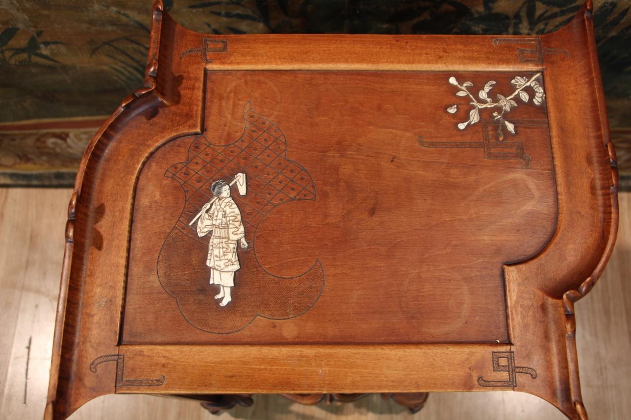Work table in carved and molded wood, opening with a flap engraved and decorated with a character and branches in bone. Generally in good condition, minimal losses in the marquetry on the top