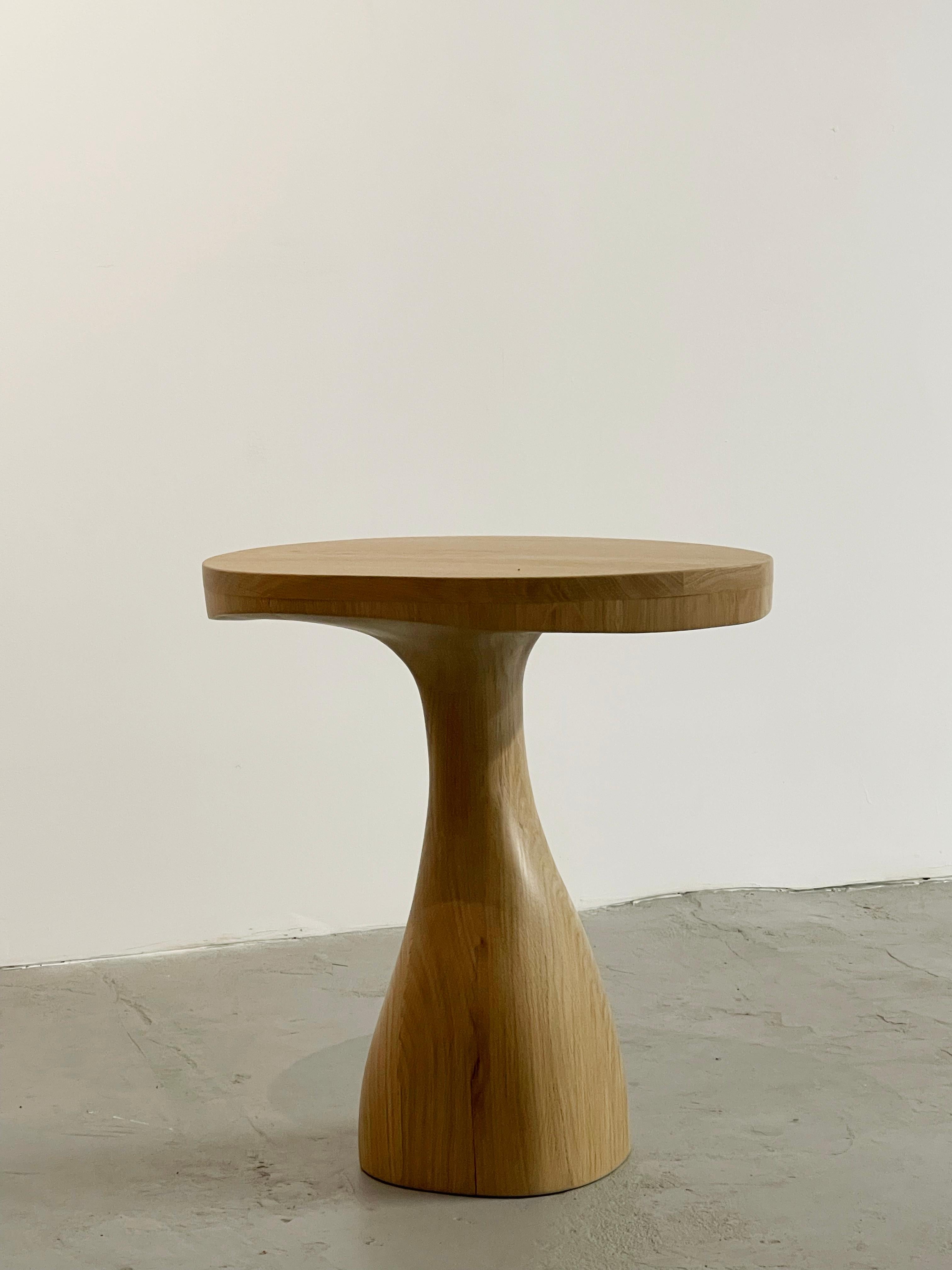 Jacques Icone s'inspire de son iconique lampadaire Leda pour créer cette table d'appoint sculptée intemporelle en chêne naturel massif. Le plateau de forme organique prolonge le pied central en forme de tige.

La sculpture semble en mouvement car le