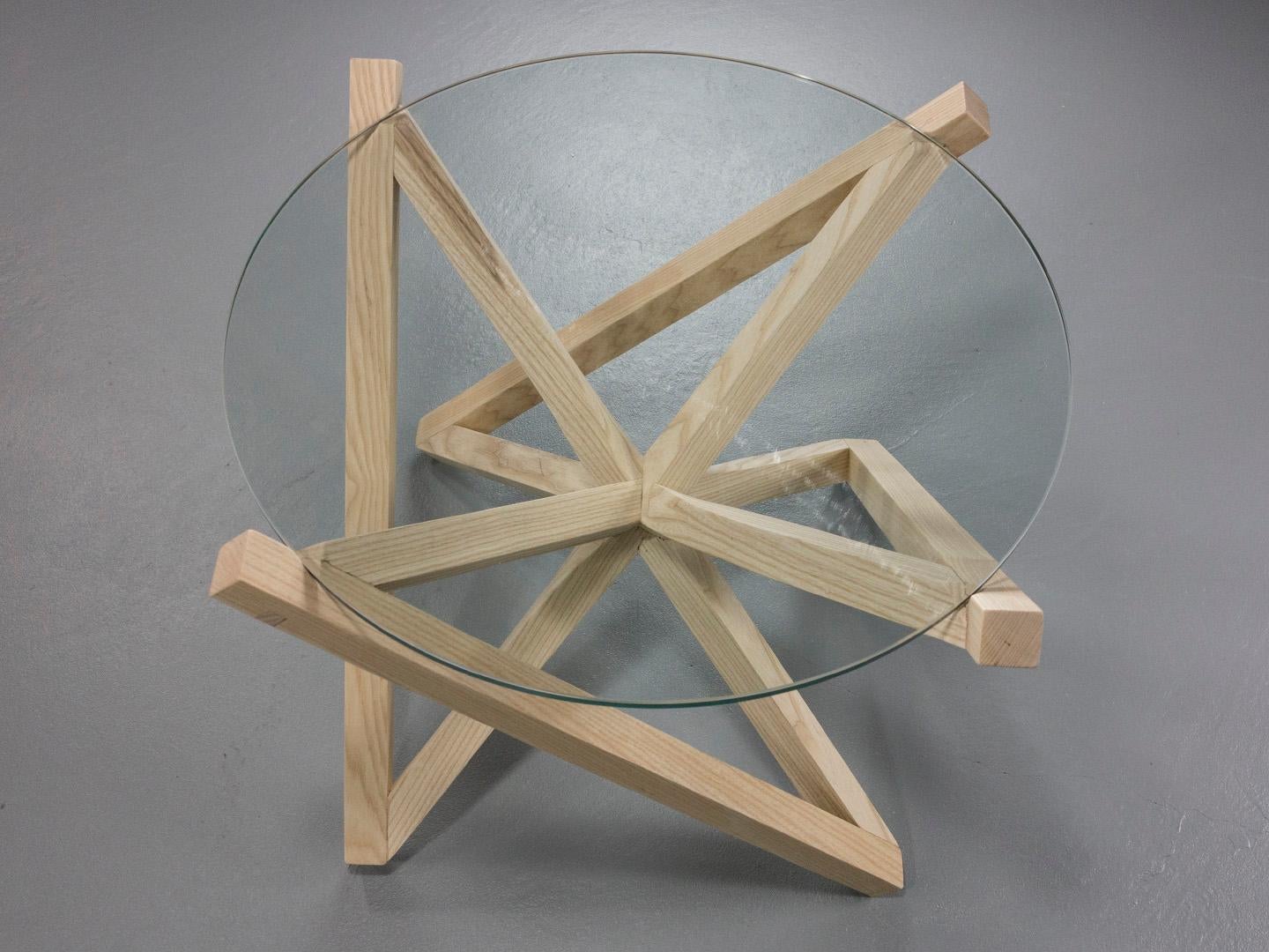 La table d'appoint Kinetic est dotée d'une base en frêne blanc qui supporte un plateau en verre trempé. La base prend une pose dynamique, mais équilibrée, qui oscille entre un X et une étoile lorsque vous vous déplacez autour d'elle. Cette pièce est