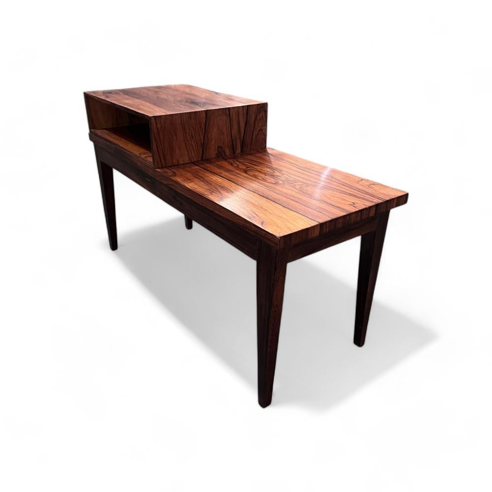 This side table with bench & storage is made of solid rosewood and rosewood veneer. Originally produced as a telephone table, today it can be adapted for use as a footstool or as a small sideboard for objects.

The wood has been expertly refinished